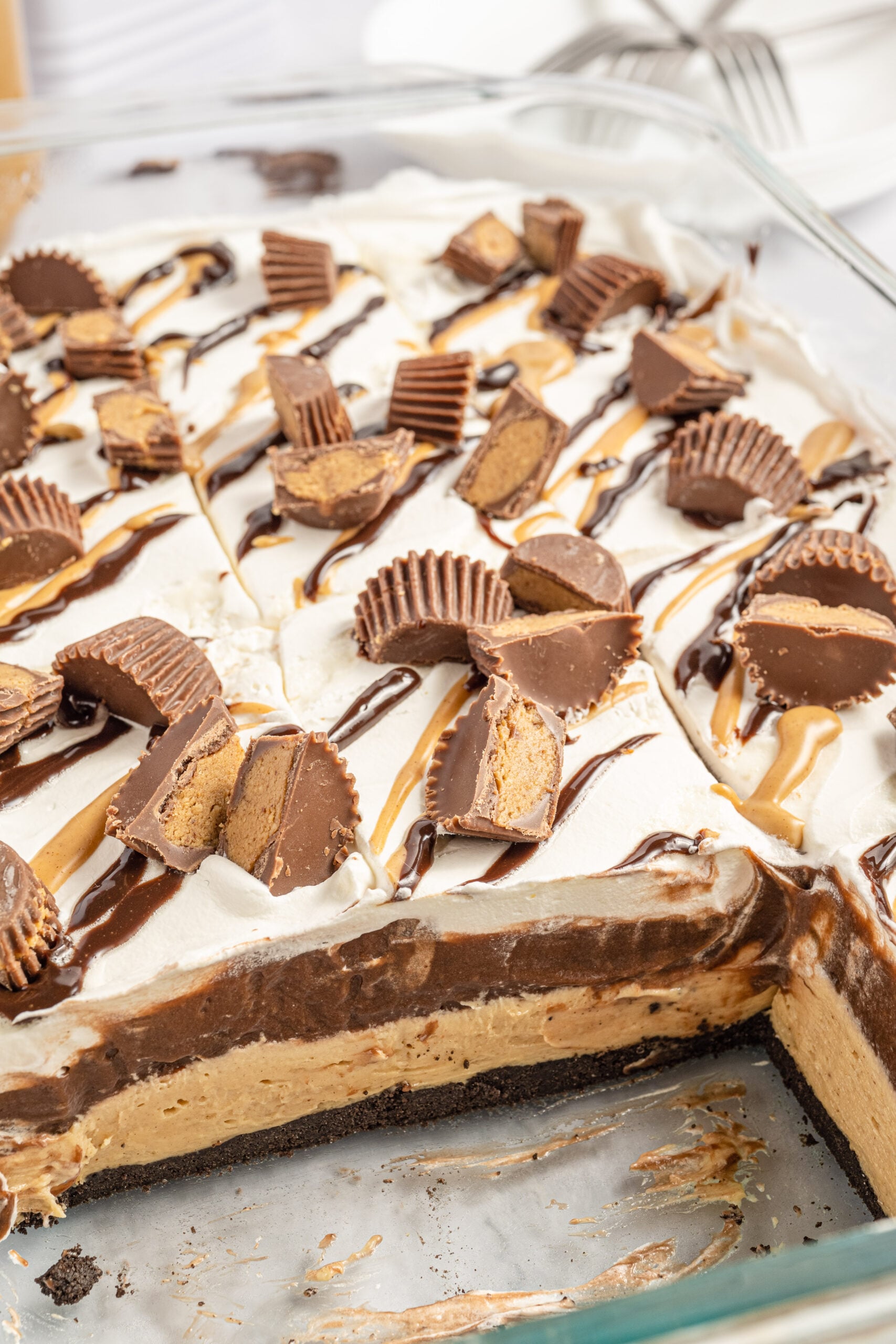 chocolate peanut butter lasagna in a glass baking pan with two slices removed.