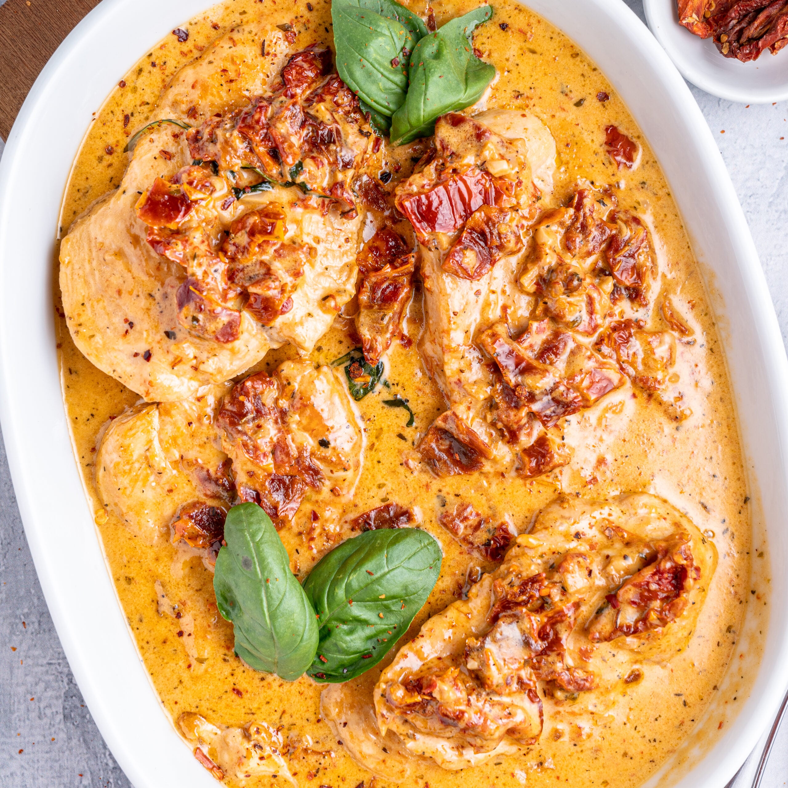 Marry Me Chicken in a white baking dish topped with fresh basil.