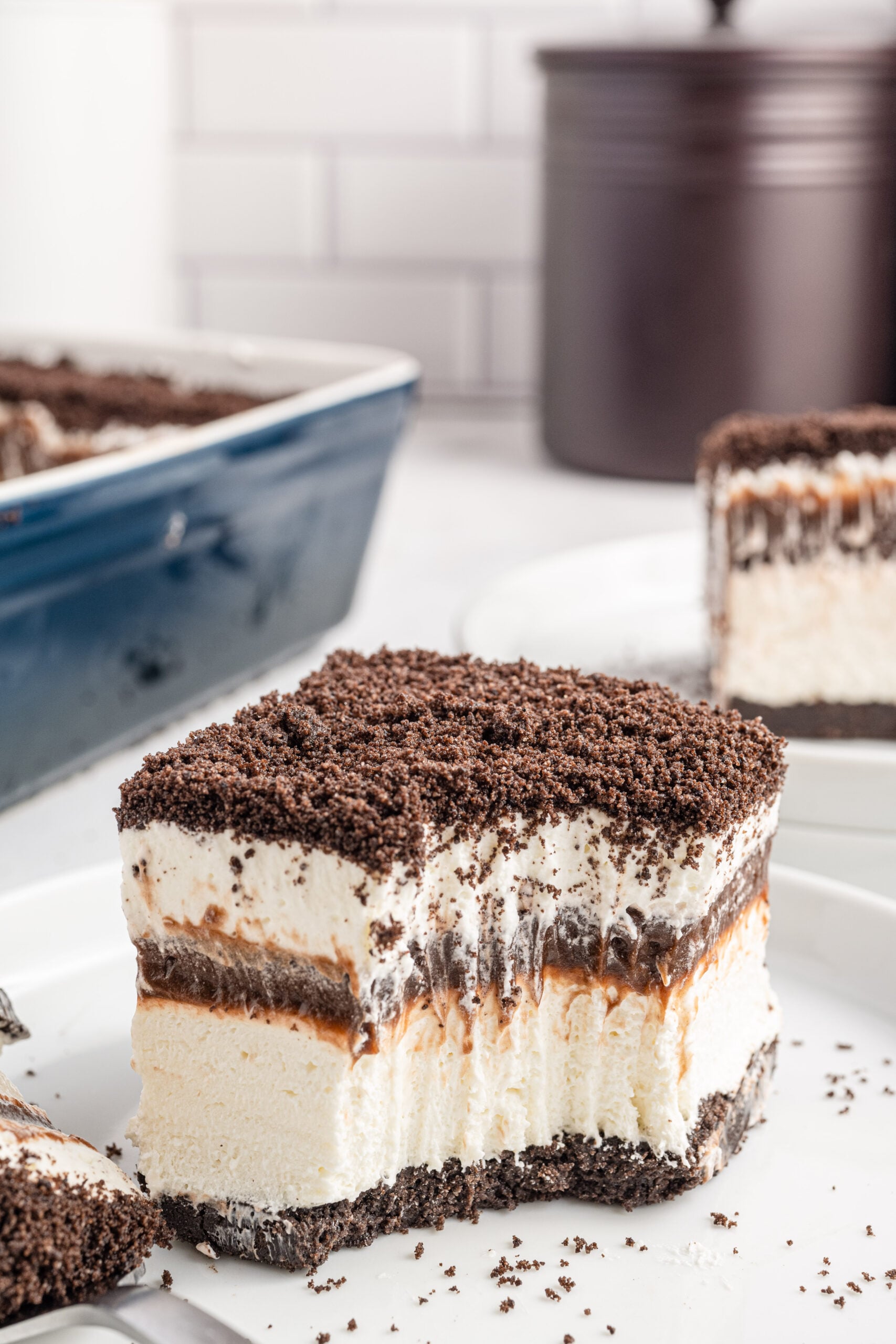 Front view of a slice of Oreo Delight on a white plate with a bite removed by a silver fork.