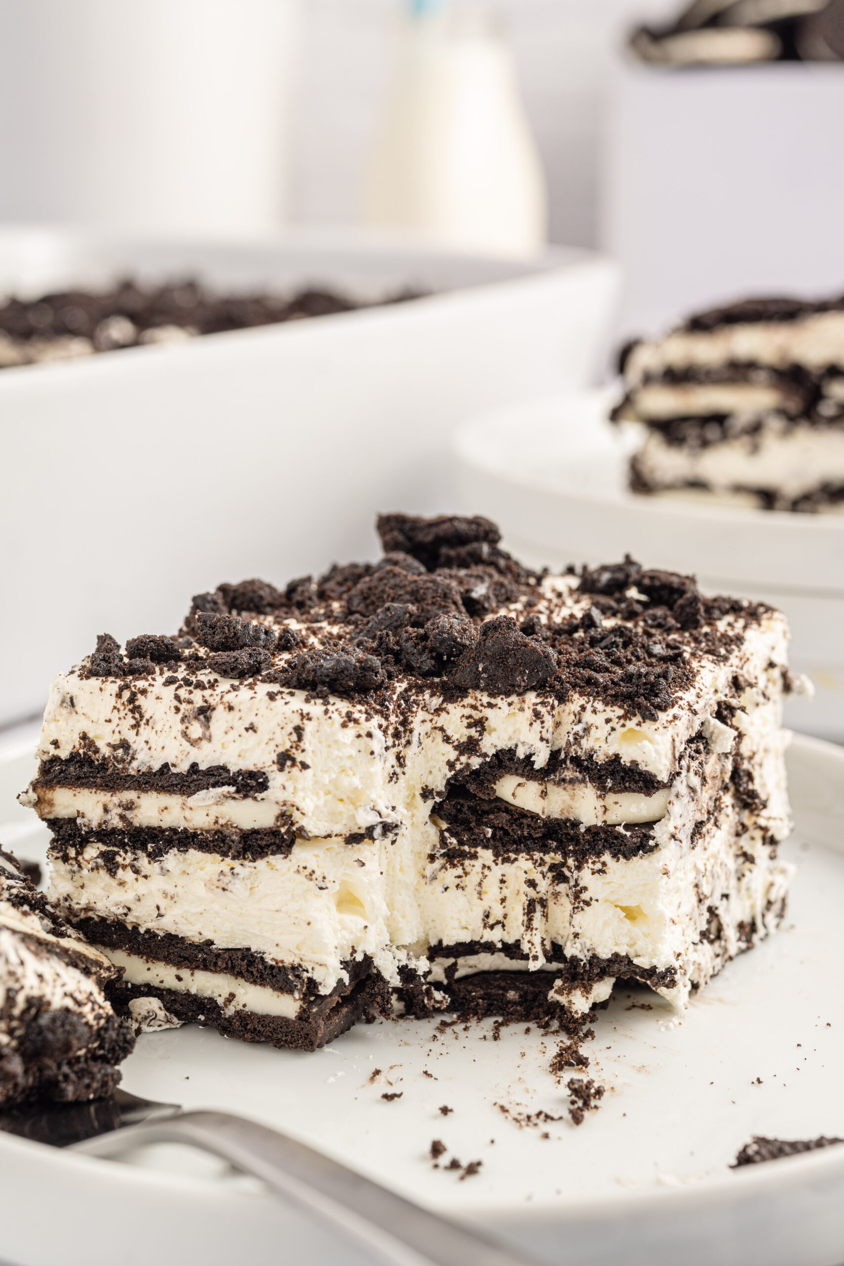 Slice of the Oreo Icebox Cake on a white plate with a bite missing