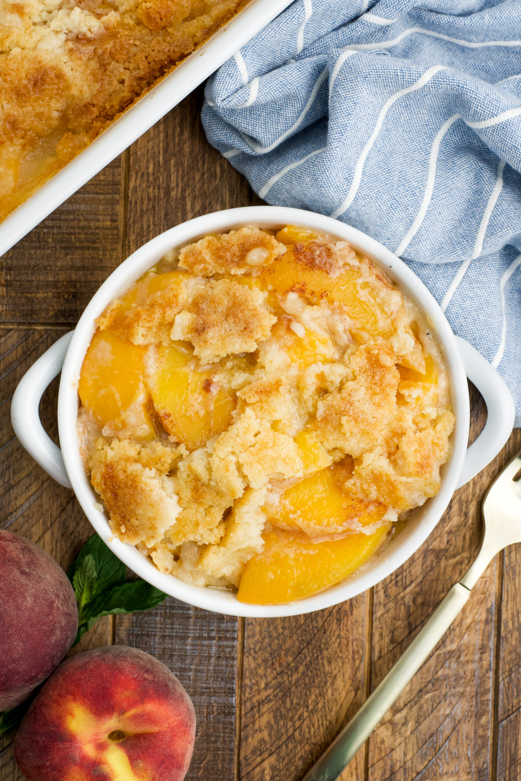 Overhead view of a serving of Peach Dump Cake in a white bowl.
