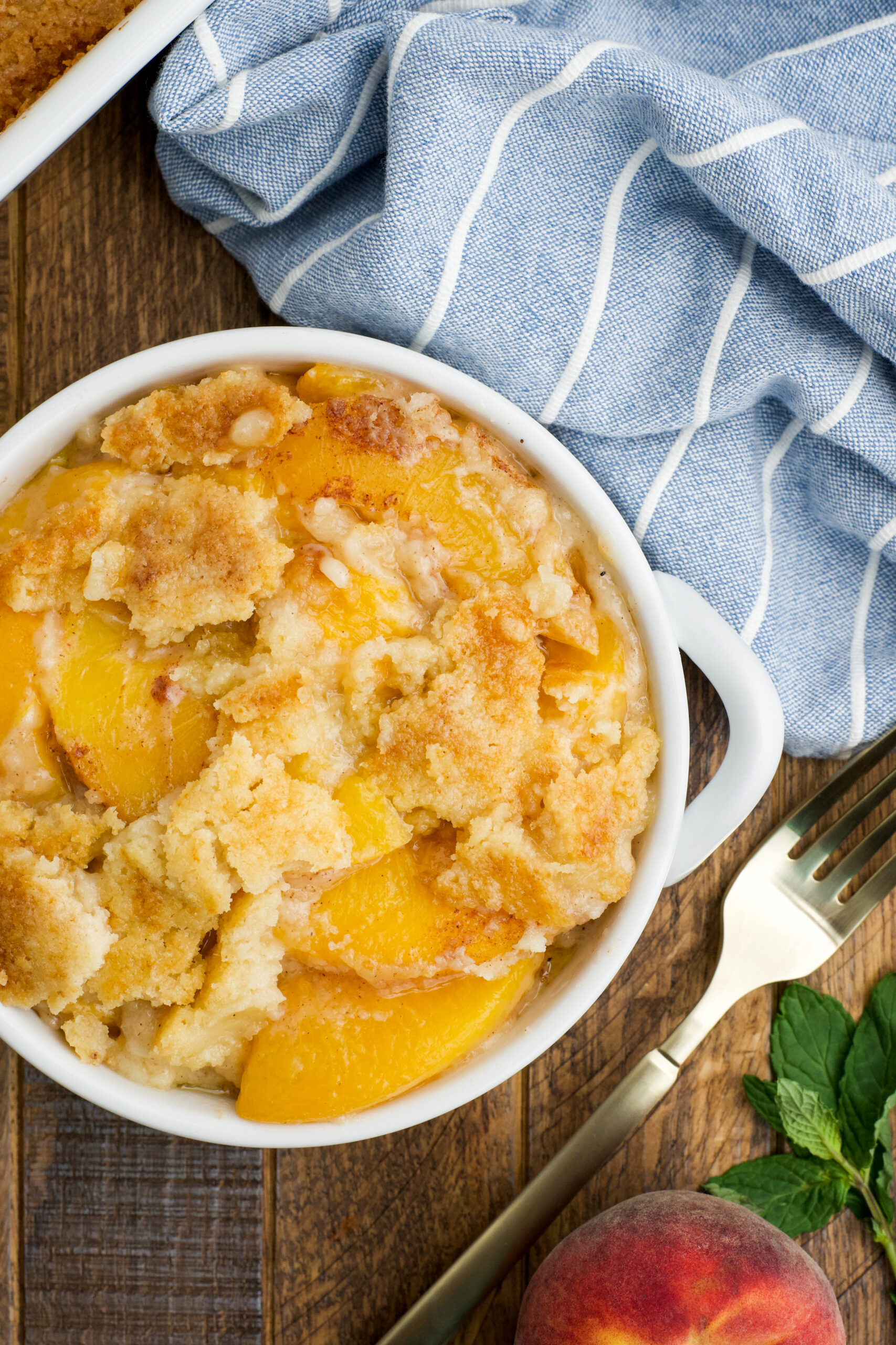 Overhead view of a serving of Peach Dump Cake in a white bowl.