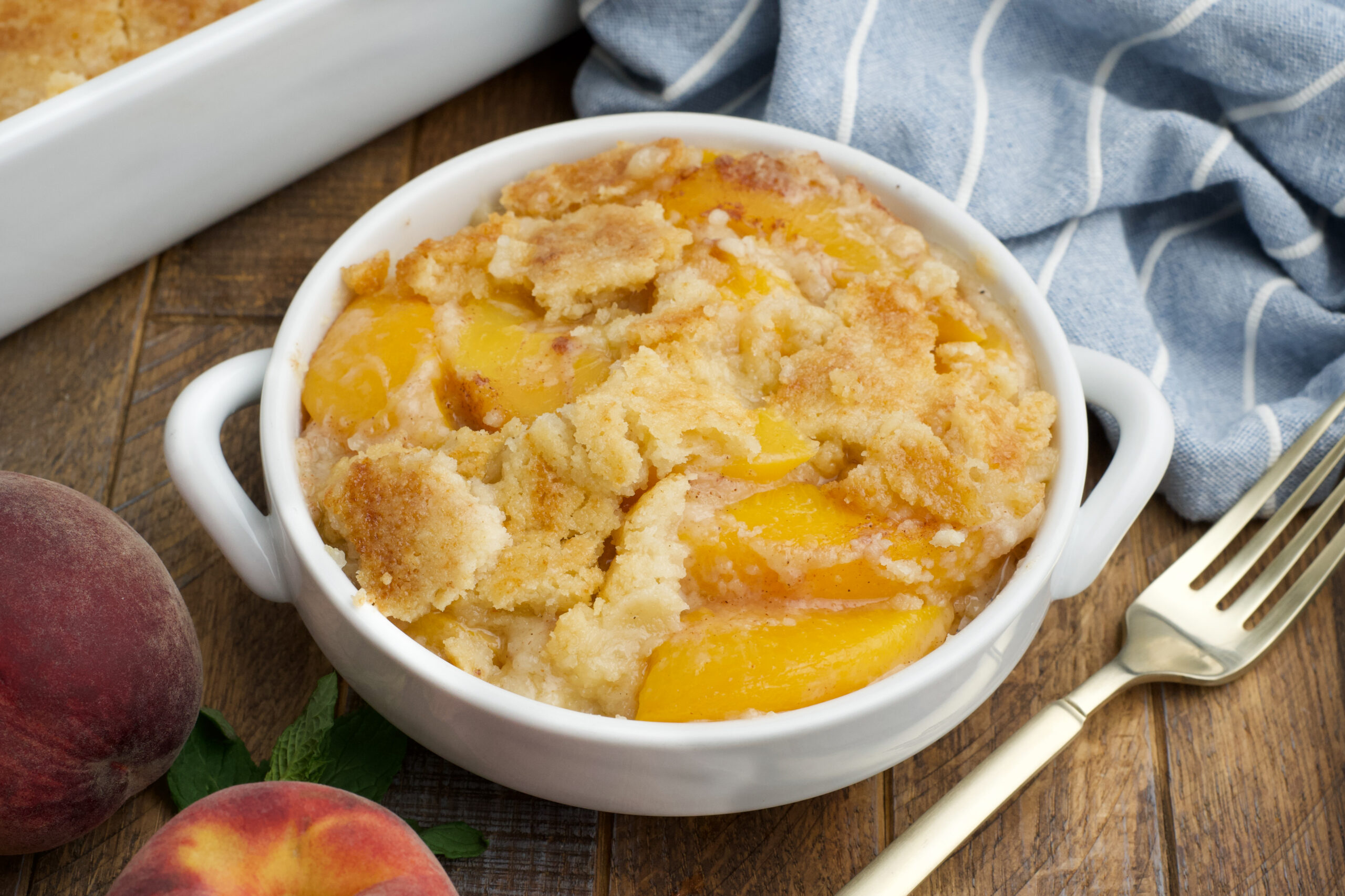 Overhead view of a serving of Peach Dump Cake in a white bowl.