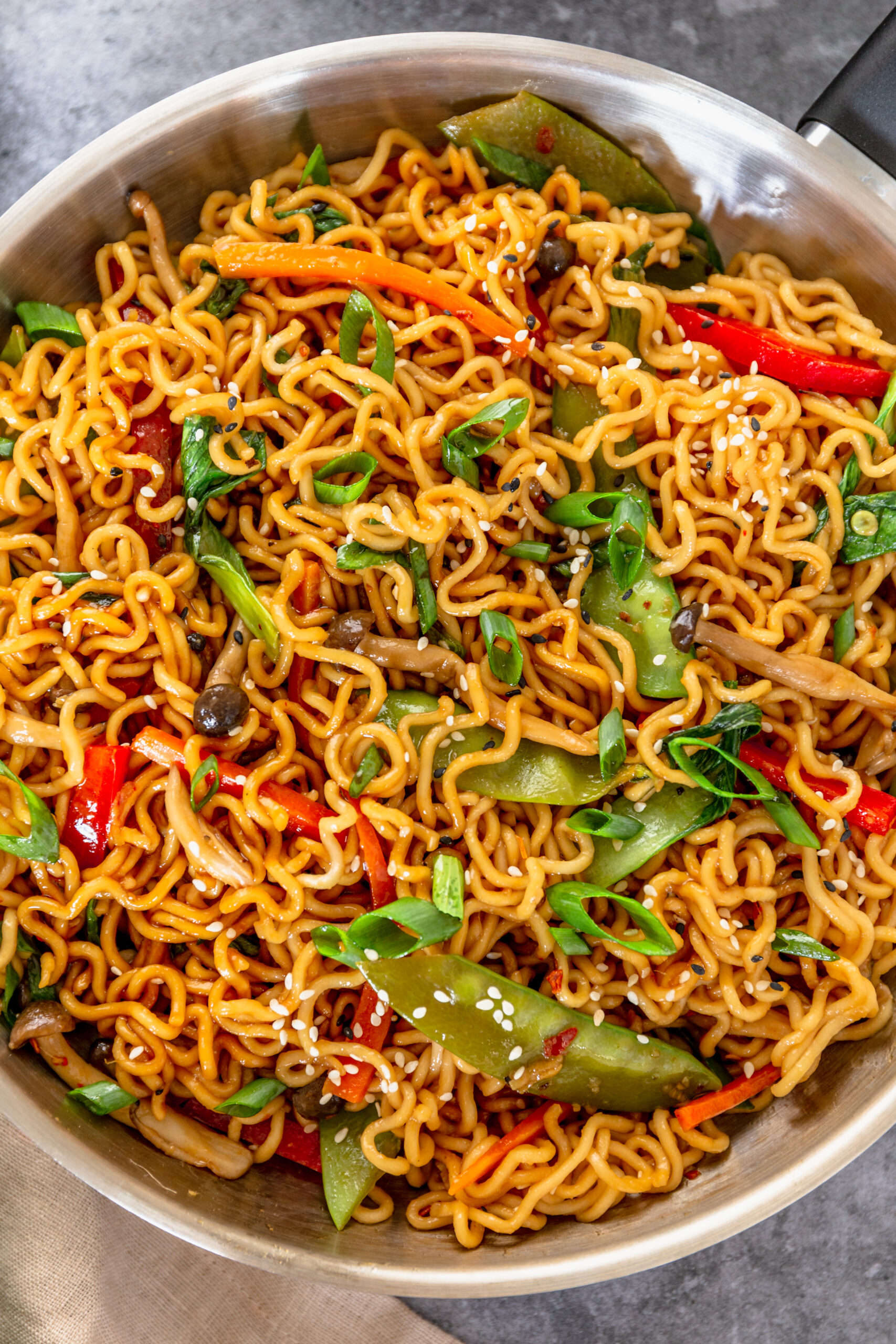 Ramen Stir Fry in a silver frying pan topped with sesame seeds.