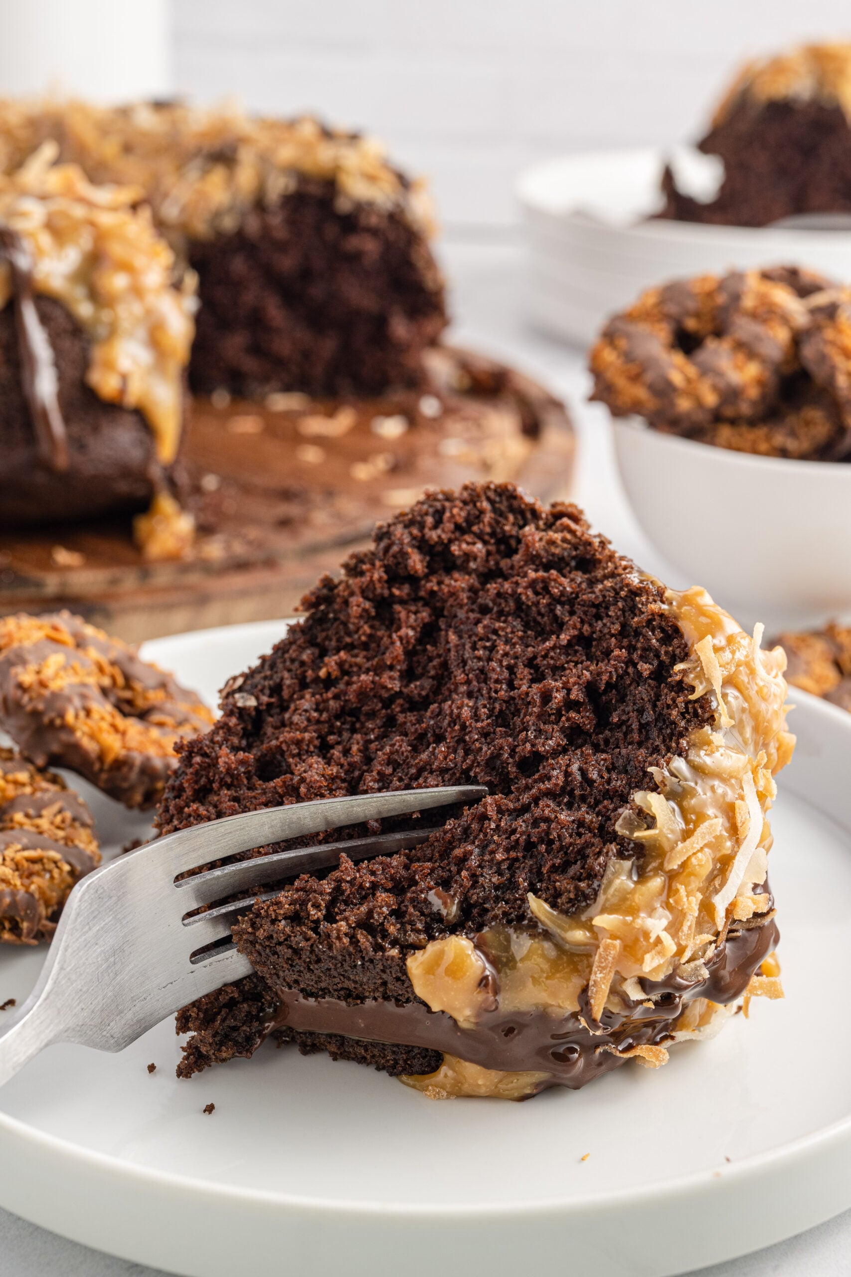 Front view of a silver fork removing a bite from a slice of Samoa Cake.