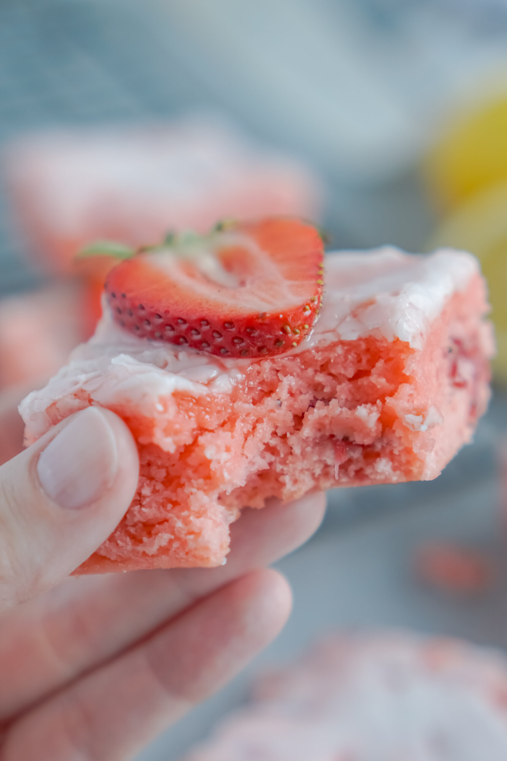 Holding up one of the strawberry brownies with a bite missing 