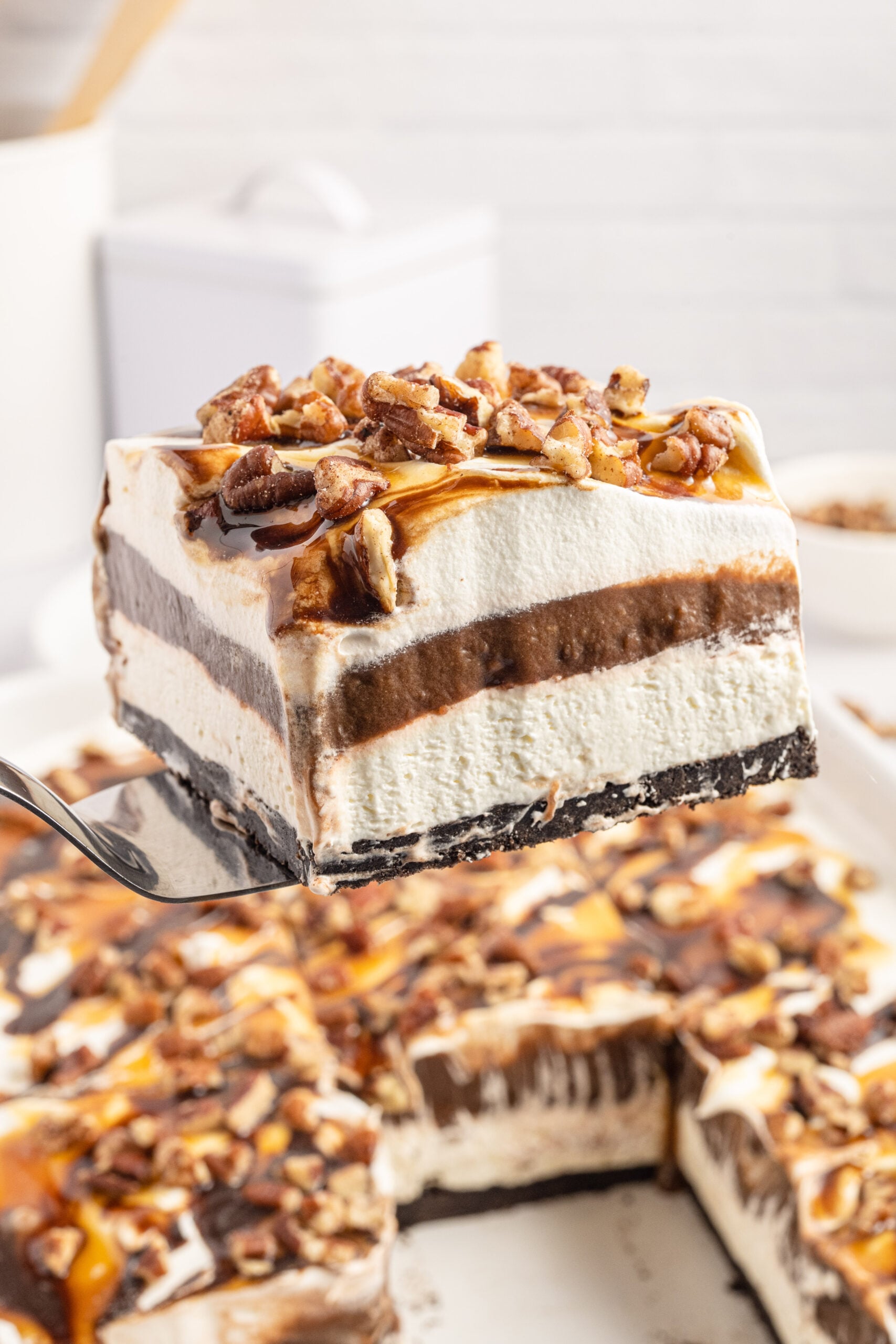 Front view of a slice of Turtle Lush on a silver cake server.