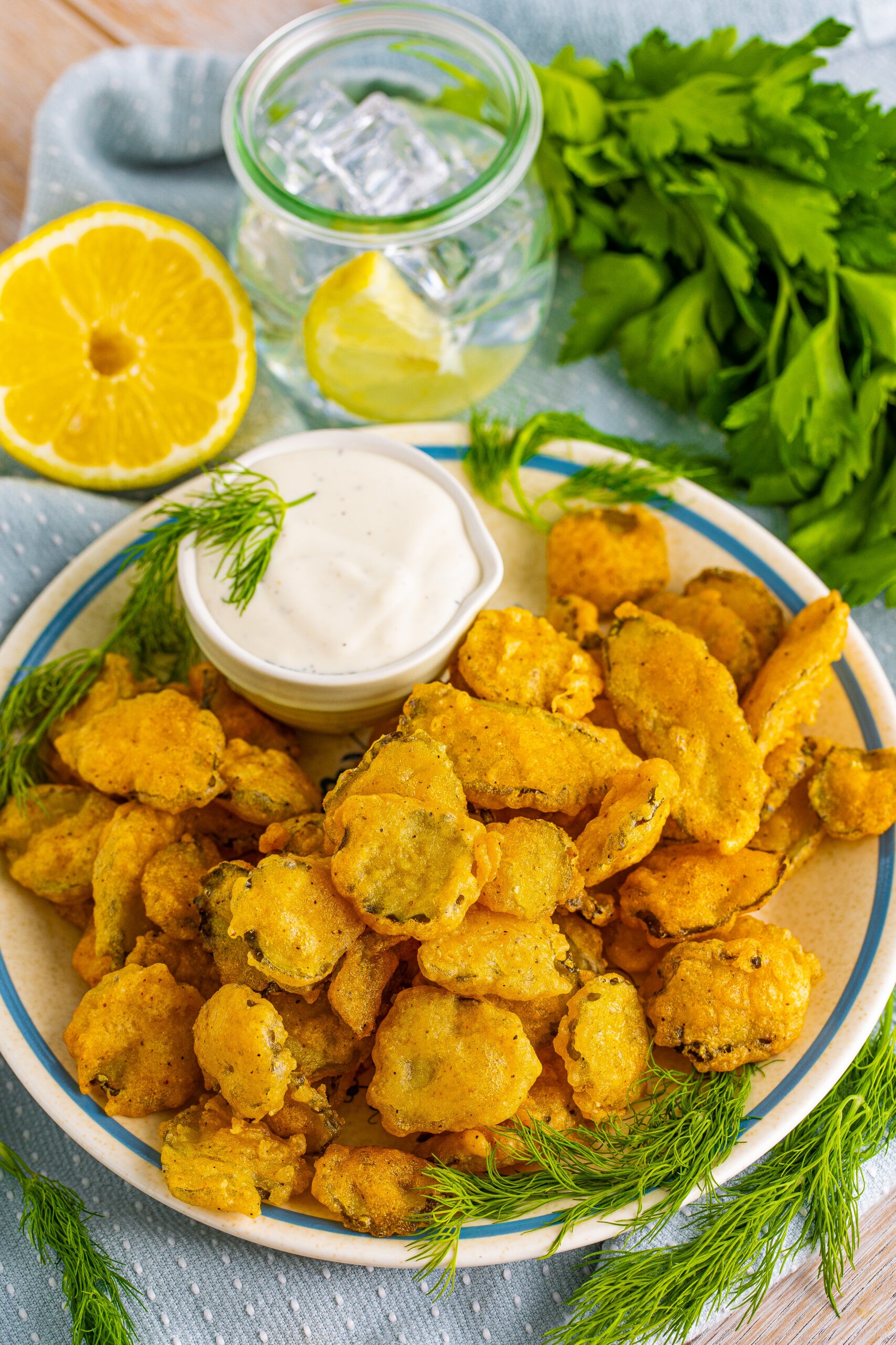 Overhead view of Fried Pickles on a white plate with ranch and fresh dill in the background.