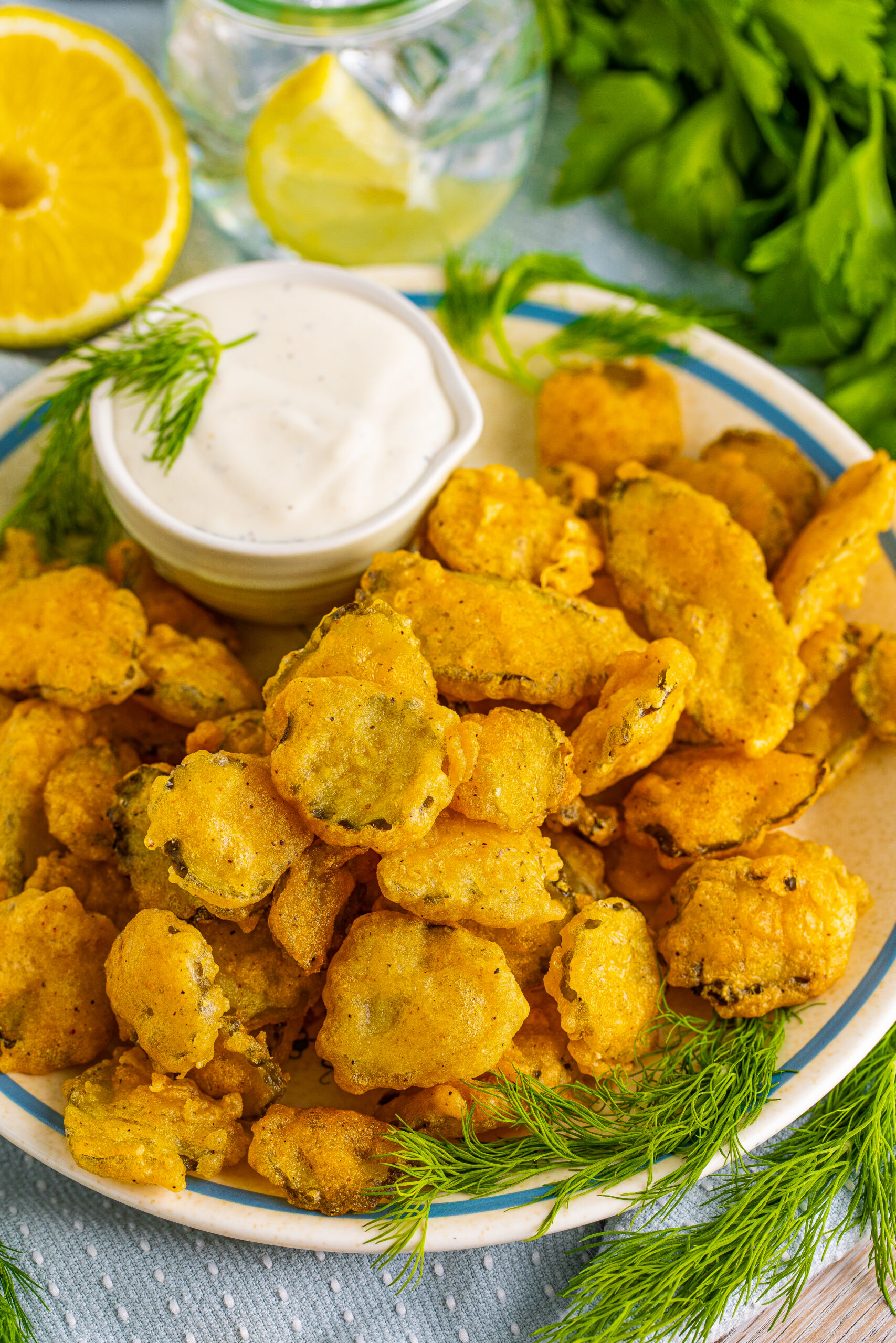 Overhead view of Fried Pickles on a white plate with ranch and fresh dill in the background.