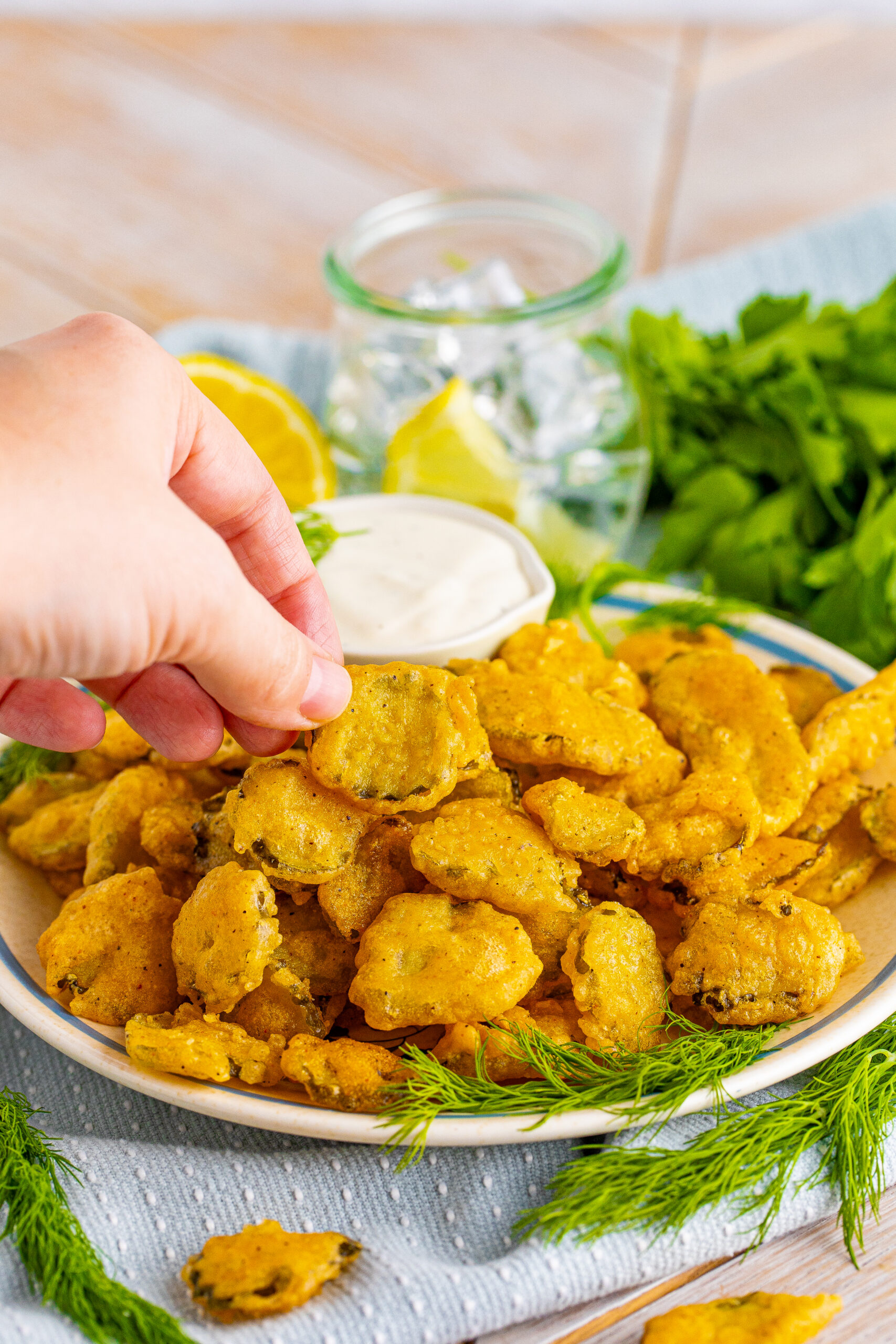 A hand removing a Fried pickle from the plate.
