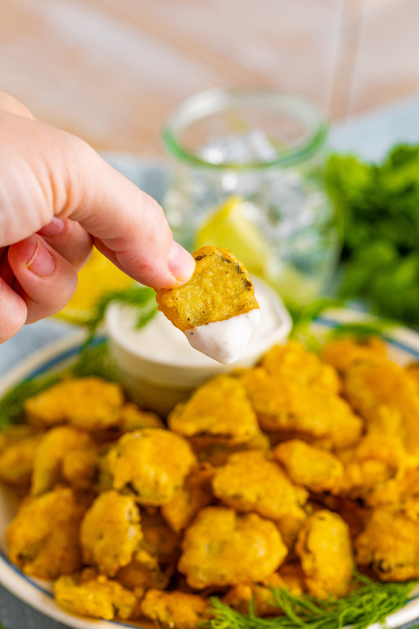 A hand holding a fried pickle that has been dipped in ranch sauce.