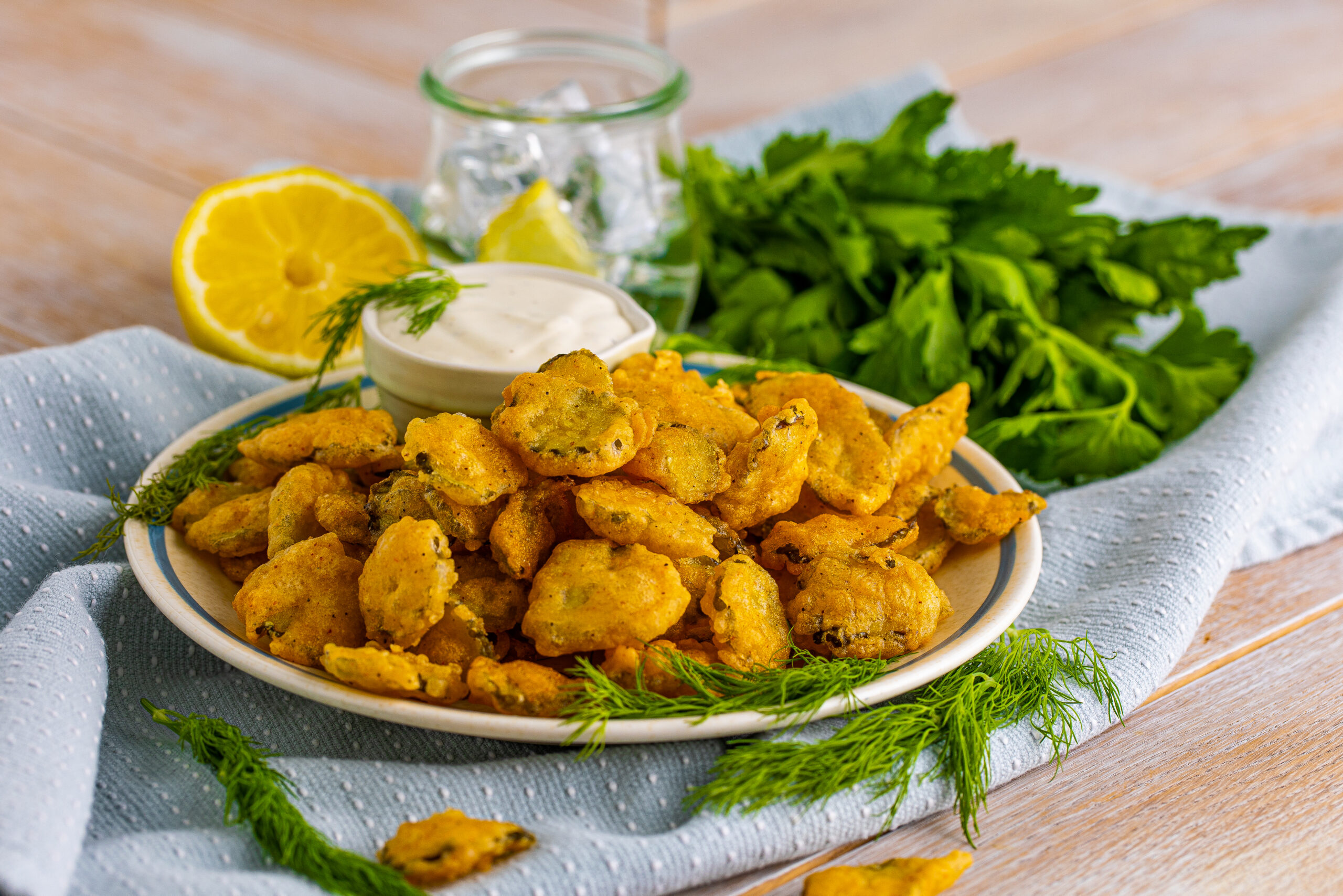 Fried Pickles on a white plate with ranch and fresh dill in the background.