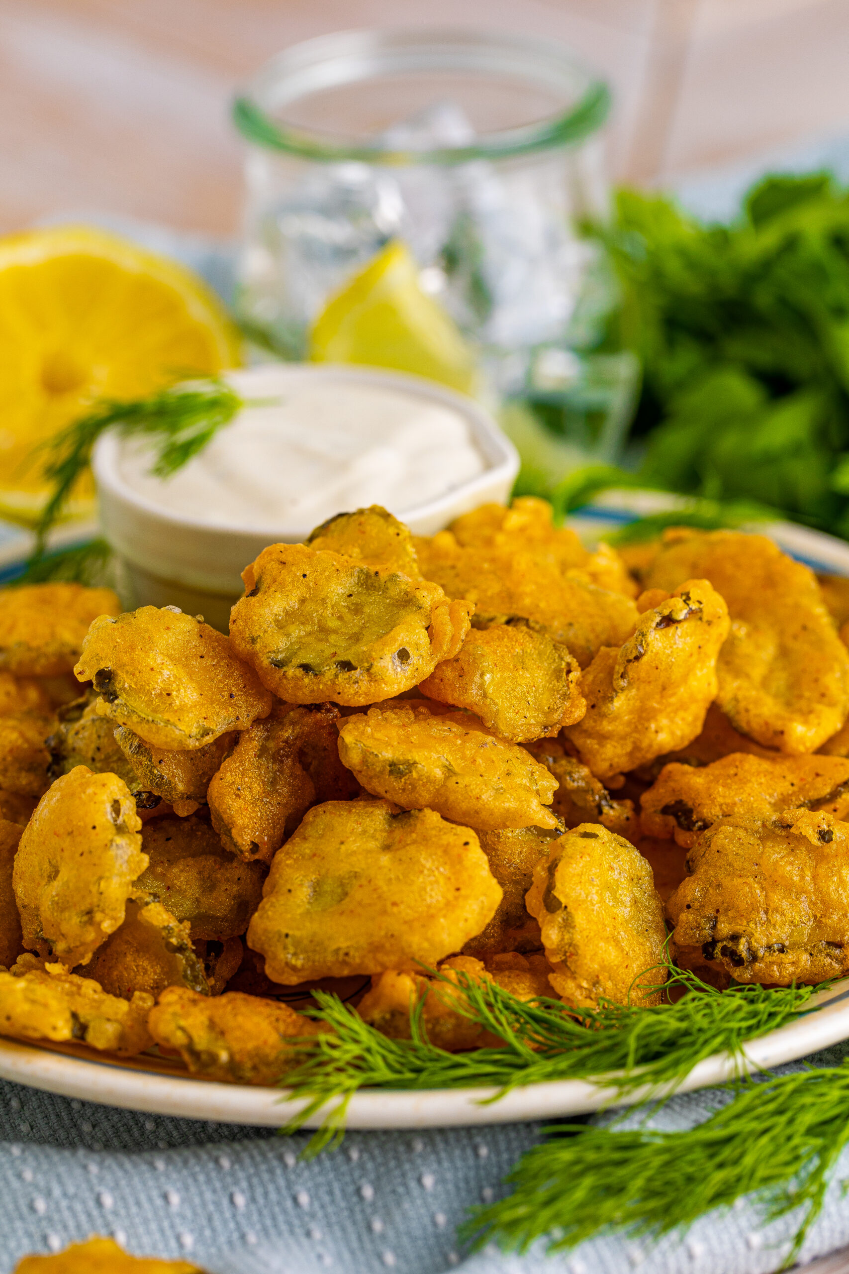 Fried Pickles on a white plate with ranch and fresh dill in the background.