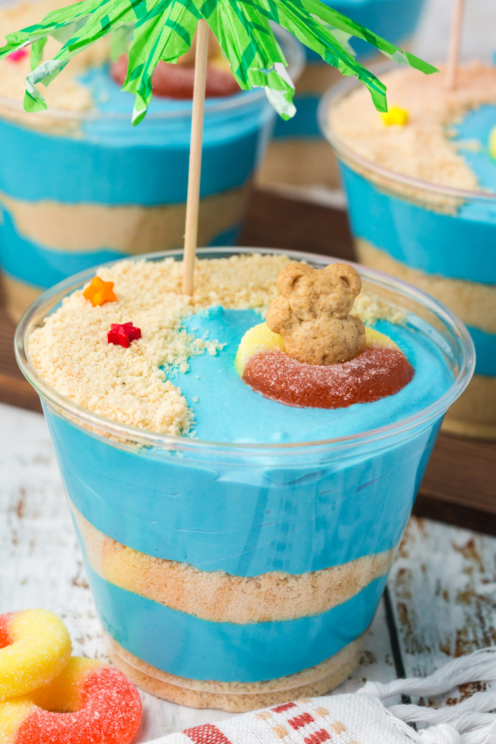 Close up view of Beach Cheesecake Pudding Cups on a white table with a green umbrella