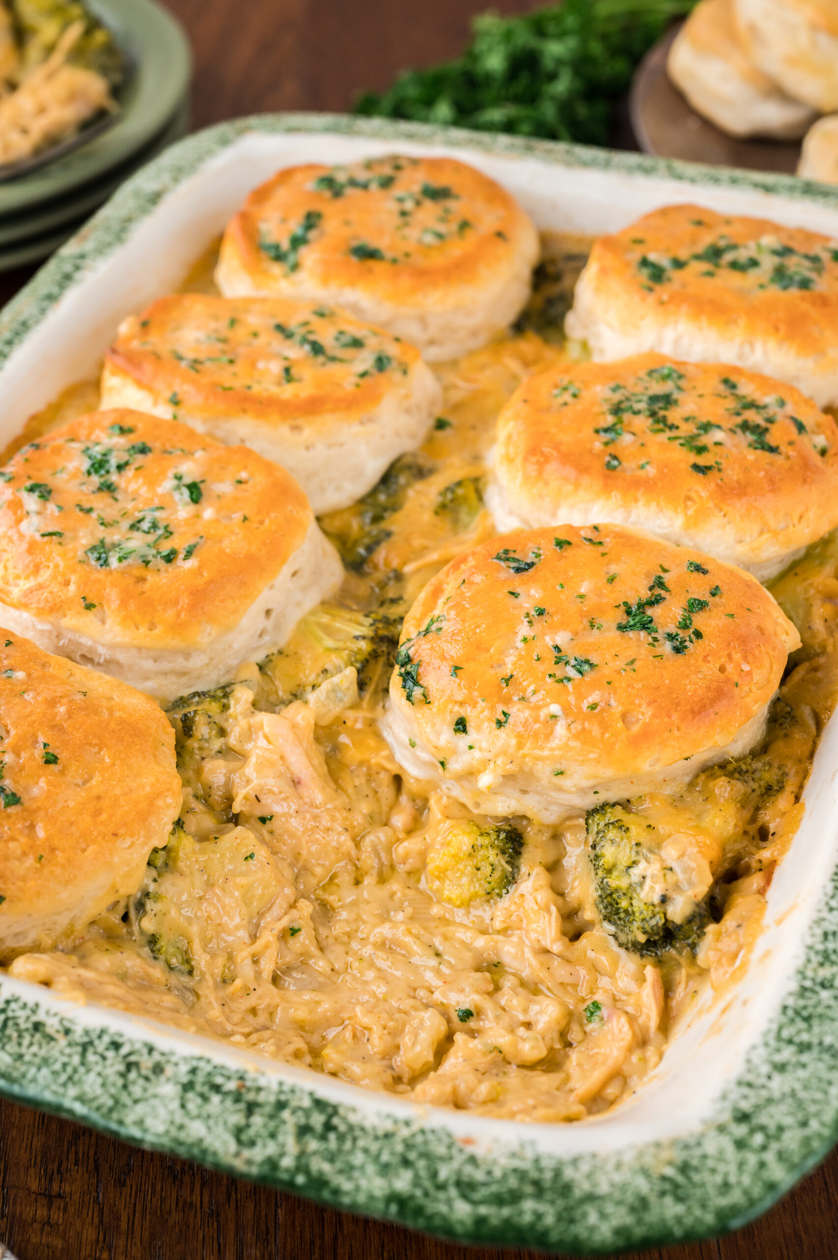 Close up view of Broccoli Cheddar Biscuit Casserole in a baking dish with one biscuit removed.