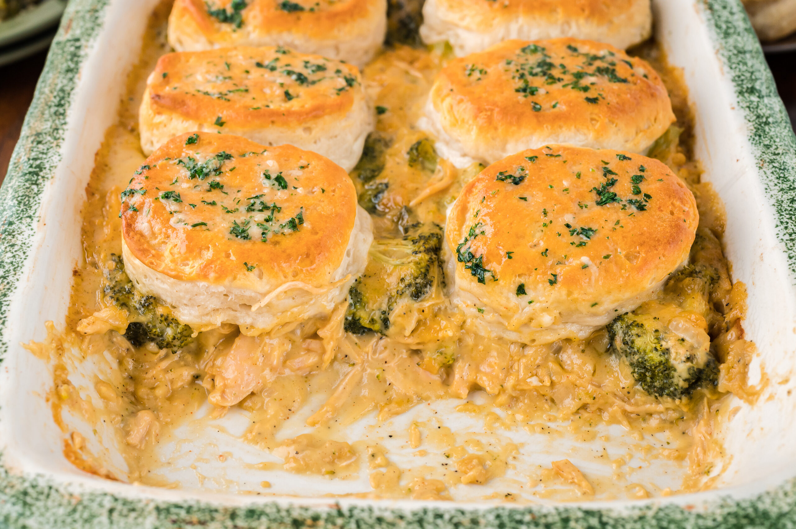 Close up view of Broccoli Cheddar Biscuit Casserole in a baking dish with two full servings removed.