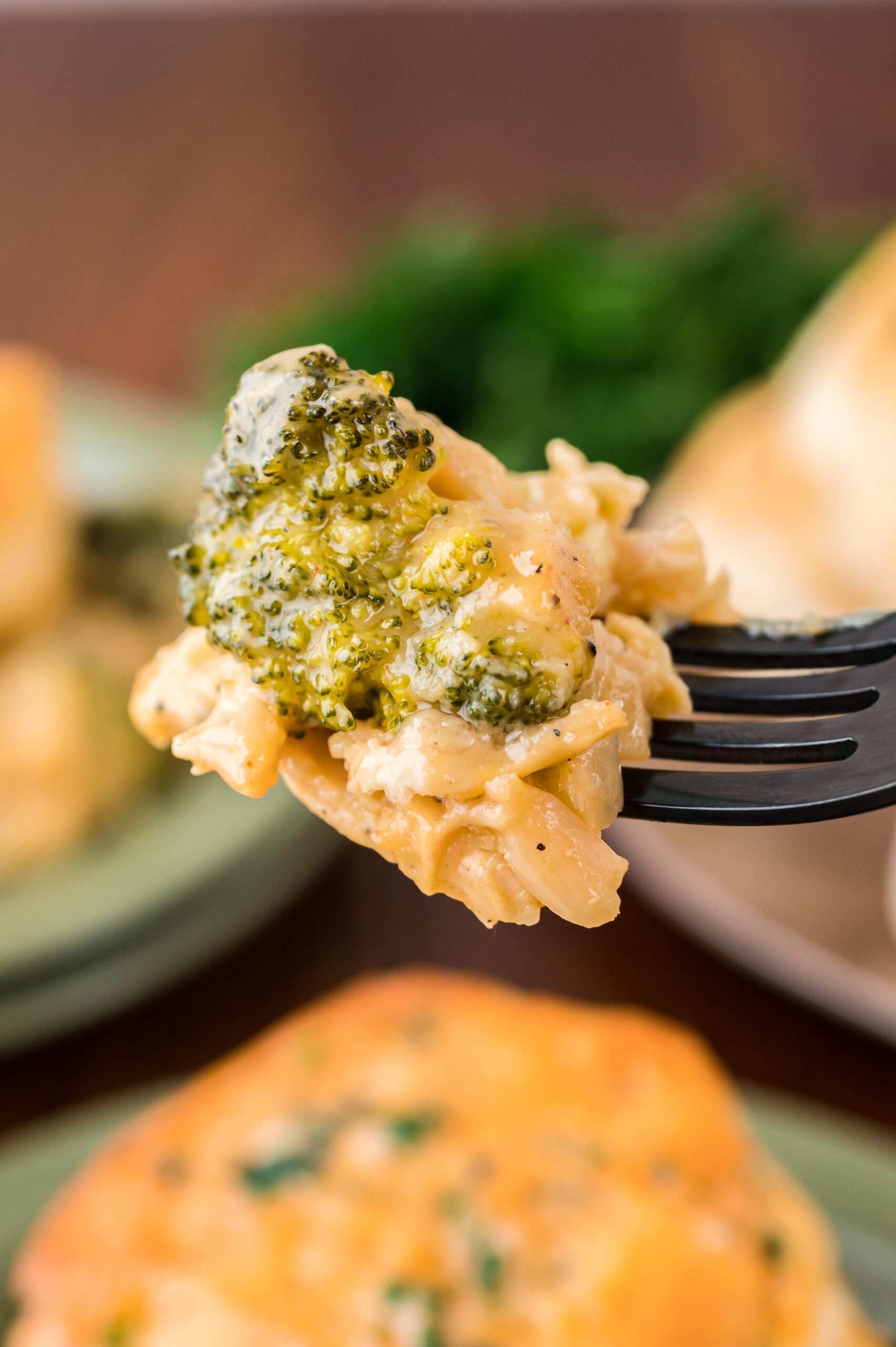 Close up view of a bite of Broccoli Cheddar Biscuit Casserole on a black fork.