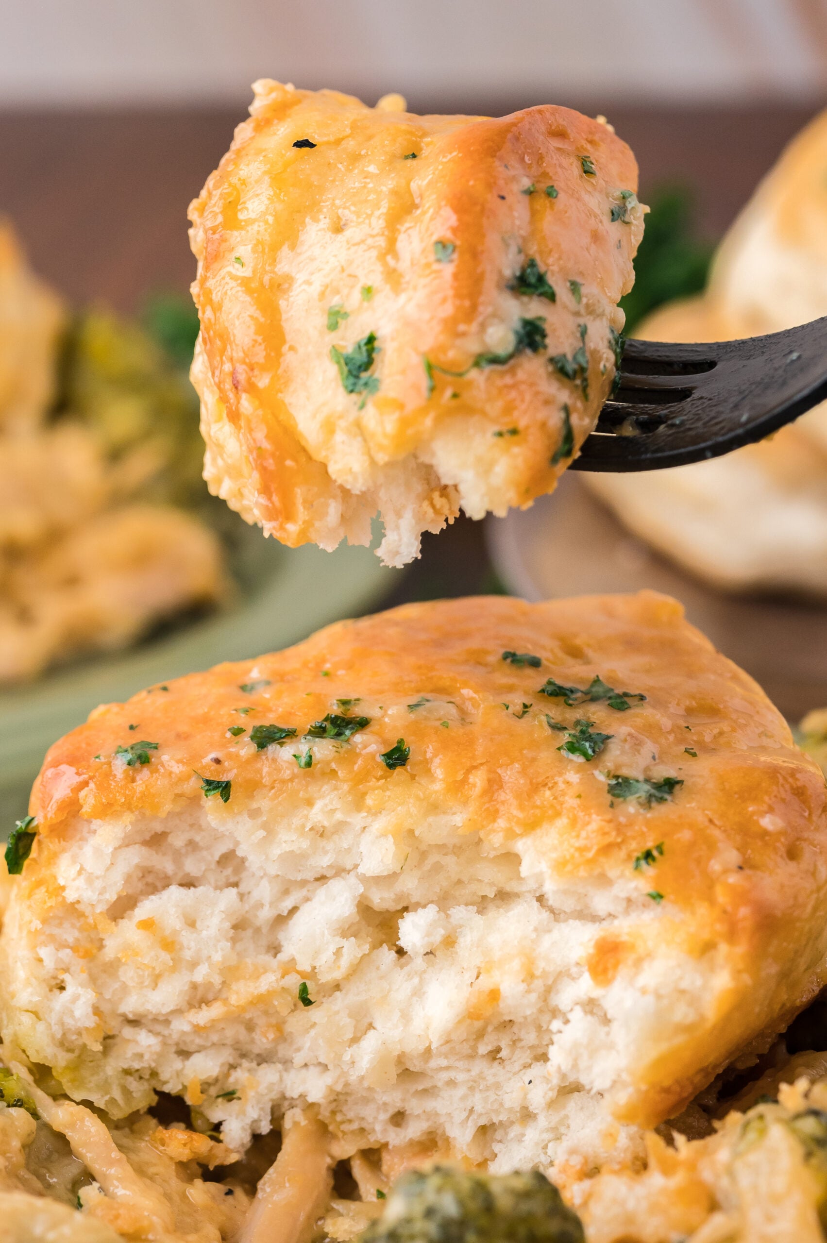 Close up view of a bite of Broccoli Cheddar Biscuit Casserole on a black fork.