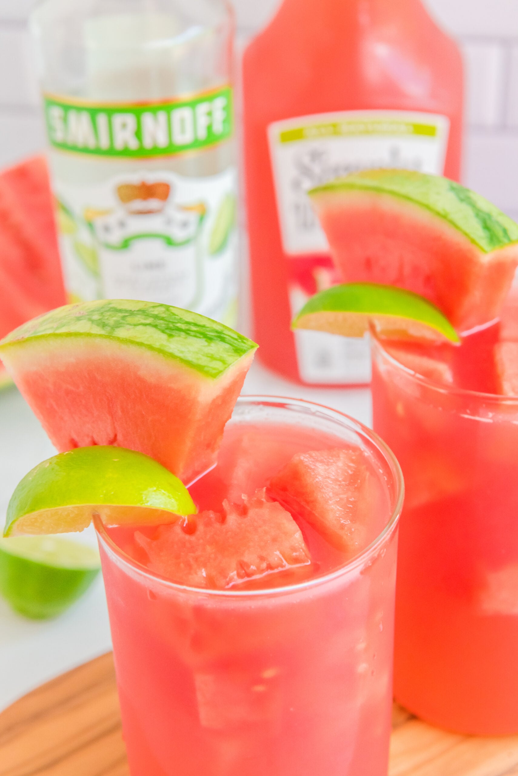 Close up view of Watermelon Cocktail in two clear glasses garnished with lime and watermelon slices.
