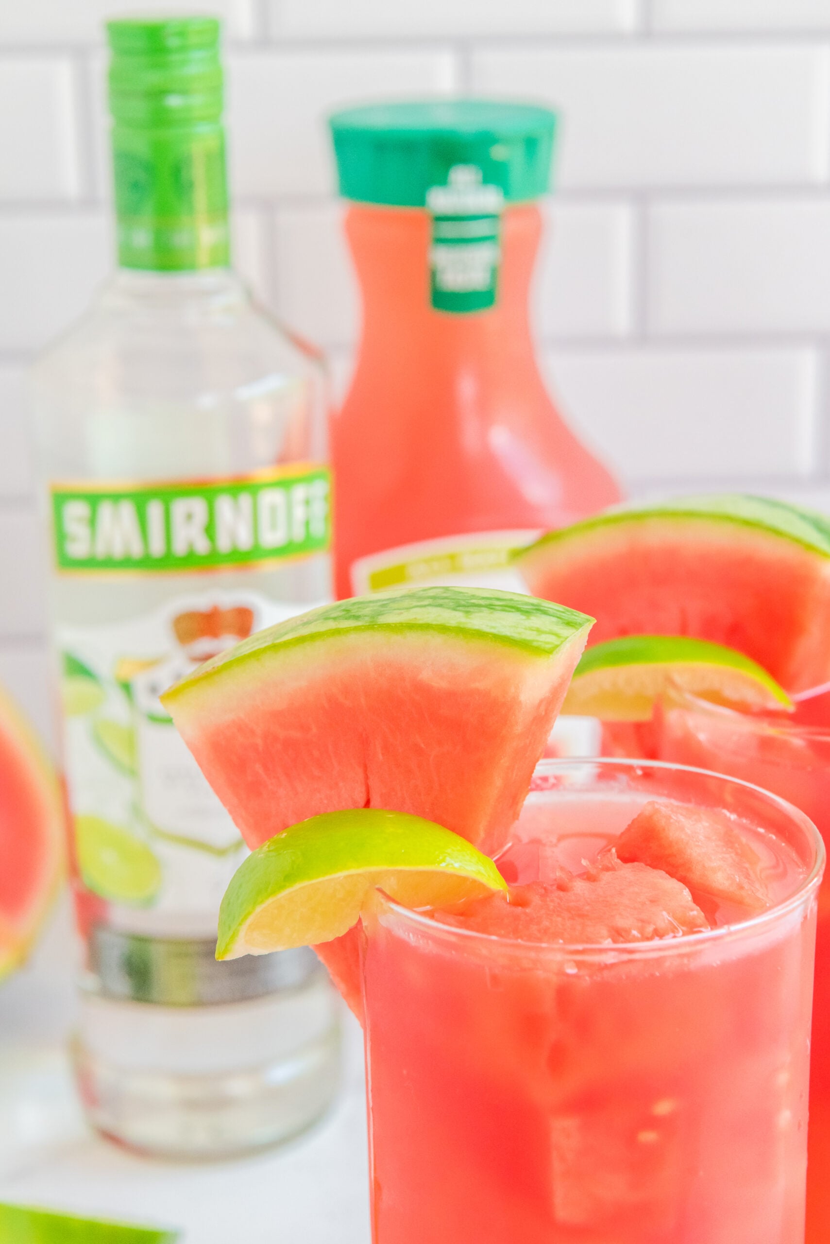 Close up view of Watermelon Cocktail in two clear glasses garnished with lime and watermelon slices.