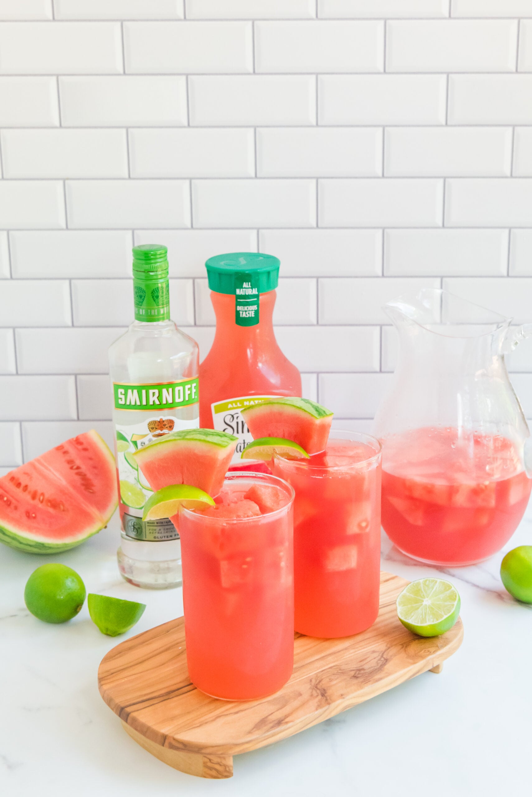 Front view of Watermelon Cocktail in two clear glasses garnished with lime and watermelon slices.