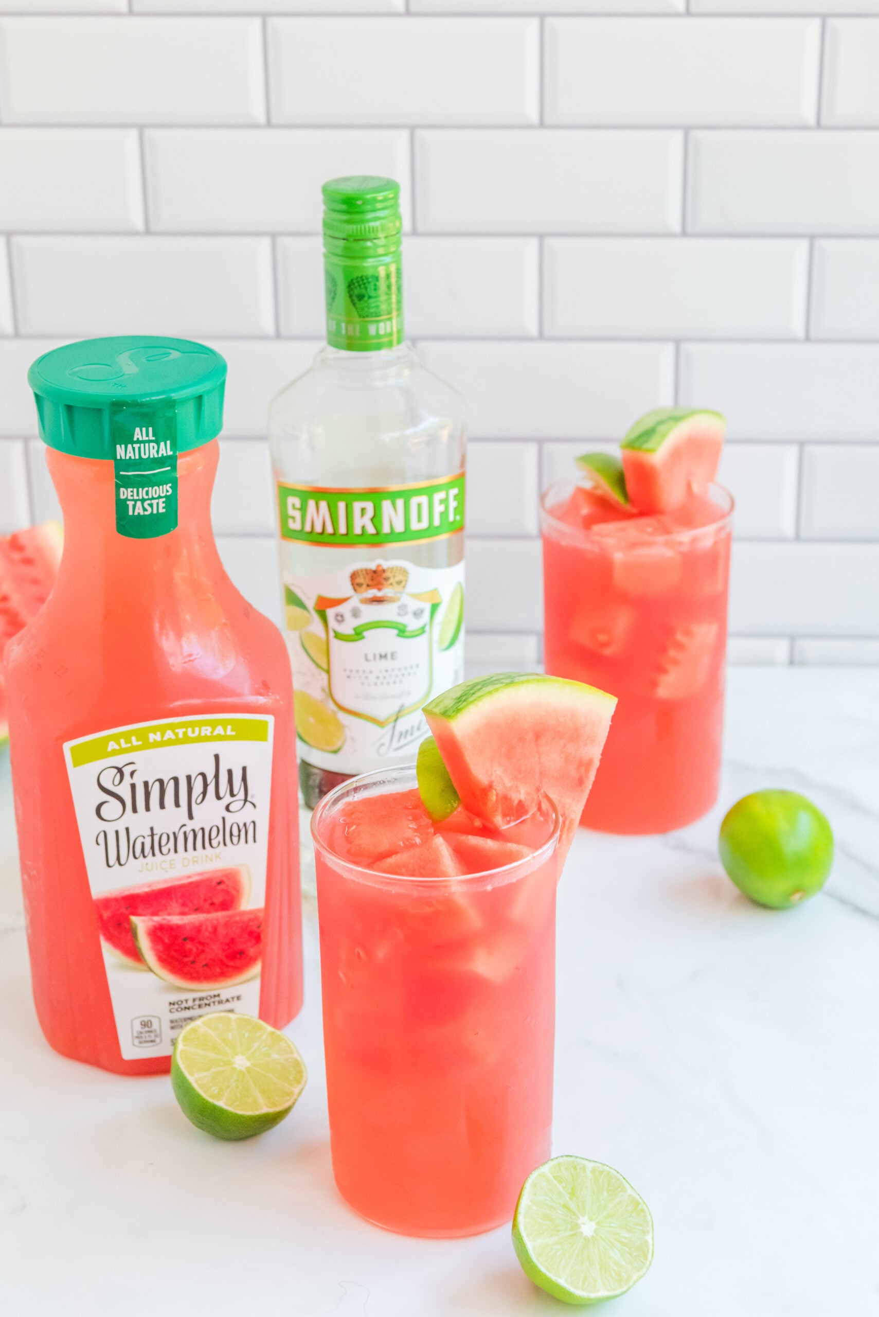 Front view of Watermelon Cocktail in two clear glasses garnished with lime and watermelon slices.