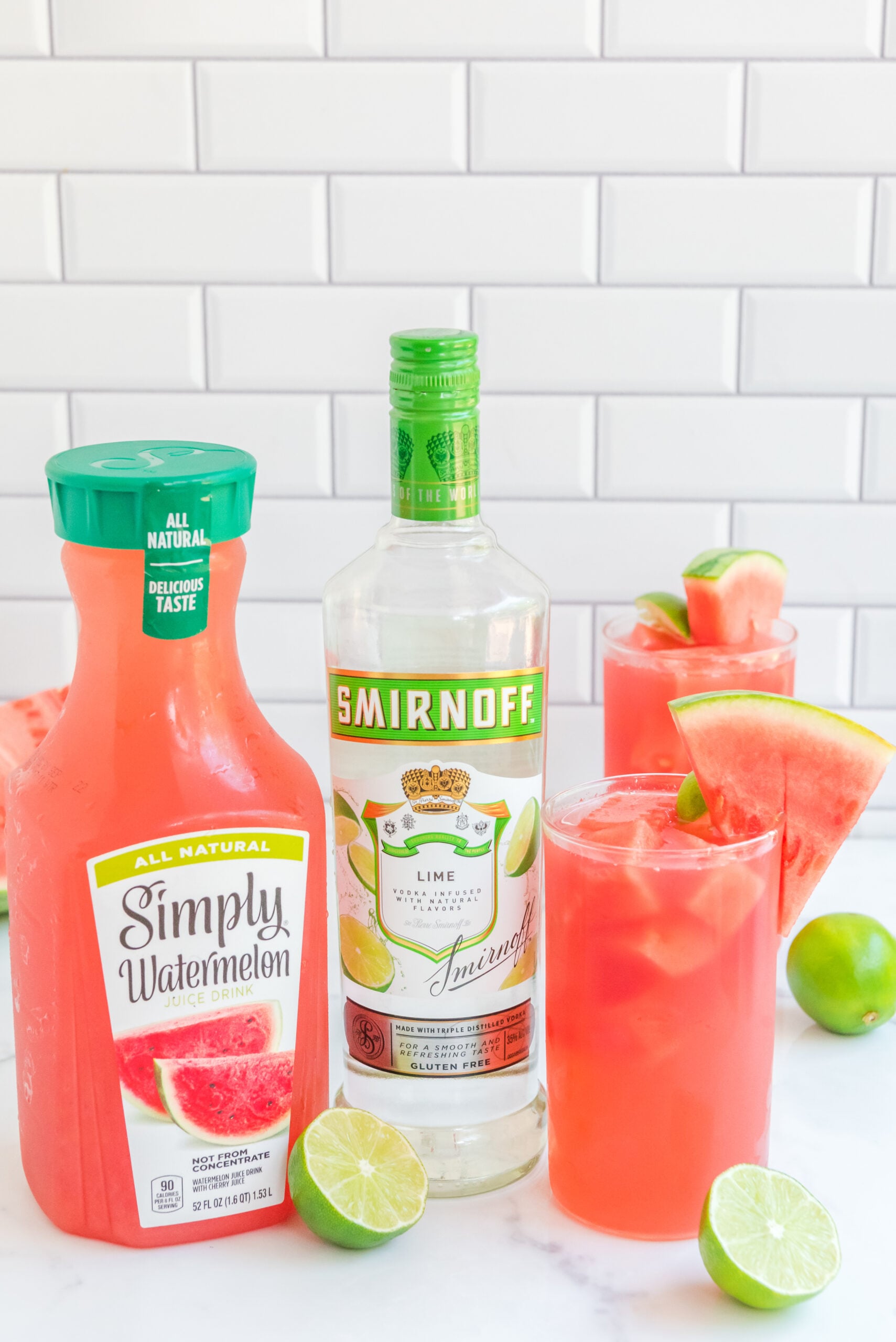 front view of Watermelon Cocktail in two clear glasses garnished with lime and watermelon slices.