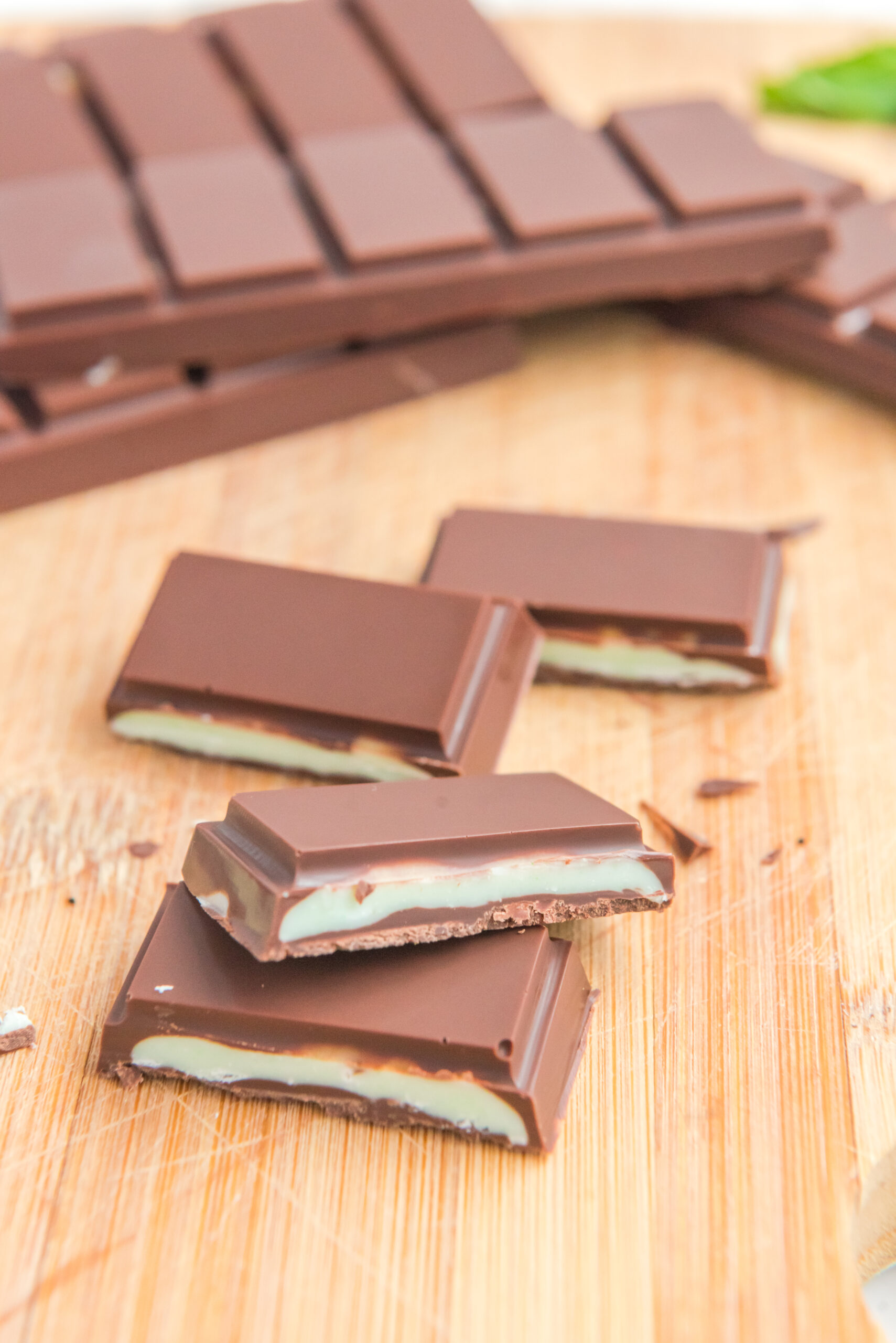 Front view of two Homemade Andes Mints stacked on a wooden cutting board.