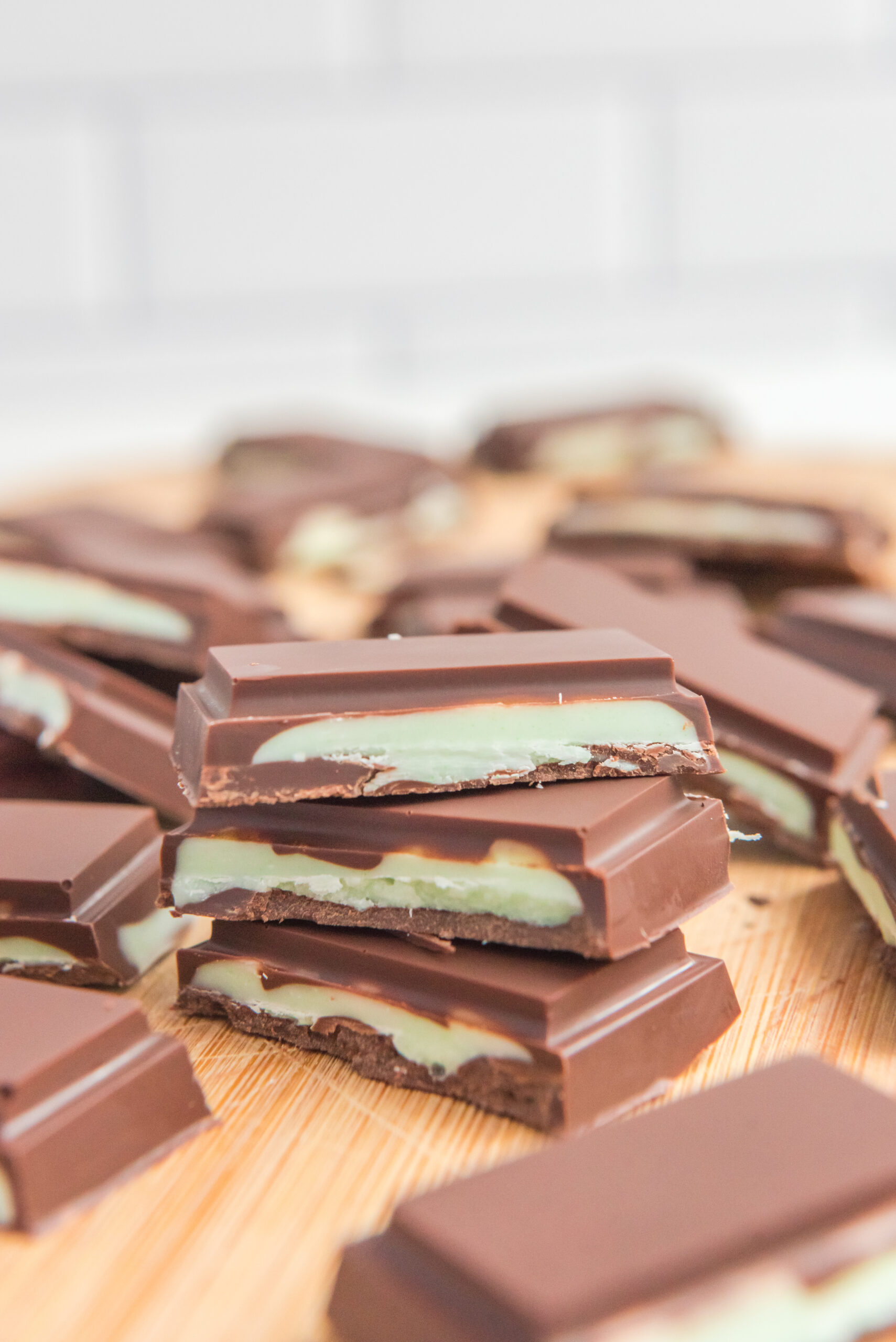 Front view of three Homemade Andes Mints stacked on a wooden cutting board.