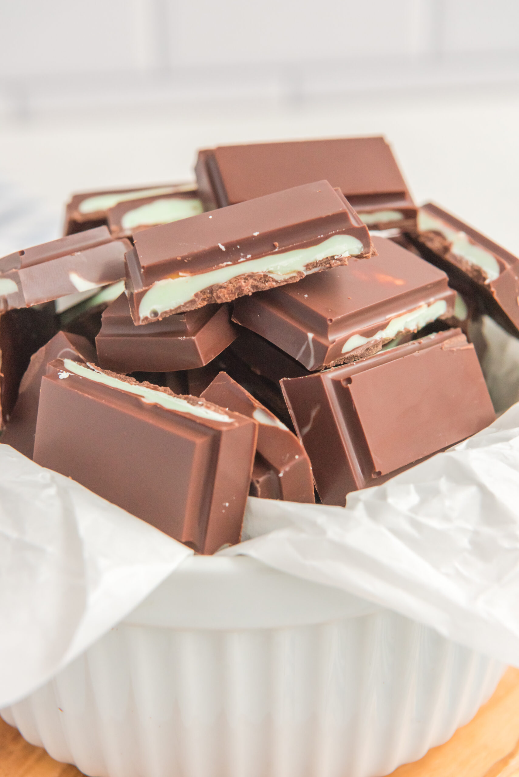 Front view of Homemade Andes Mints in a white bowl lined with parchment paper.