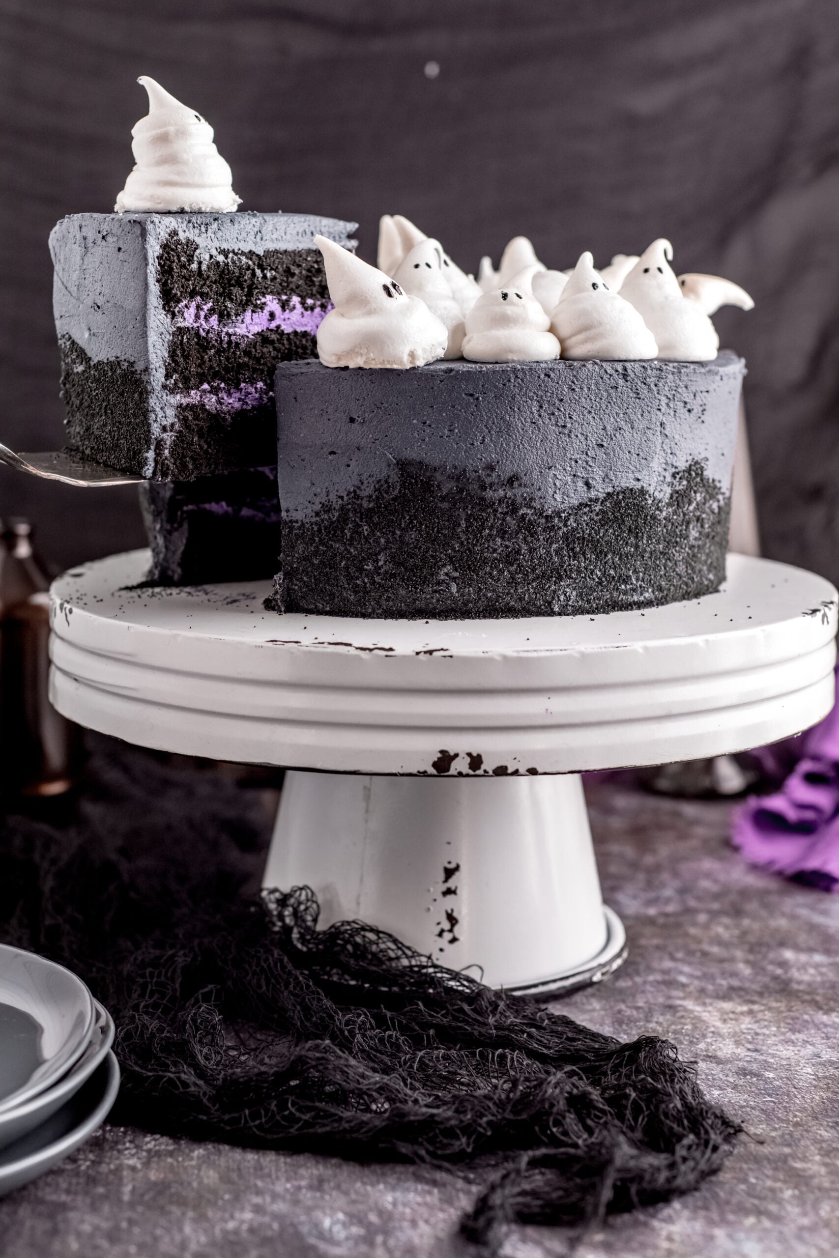 Halloween Cake on a white distressed stand with a piece being removed with a silver spatula.