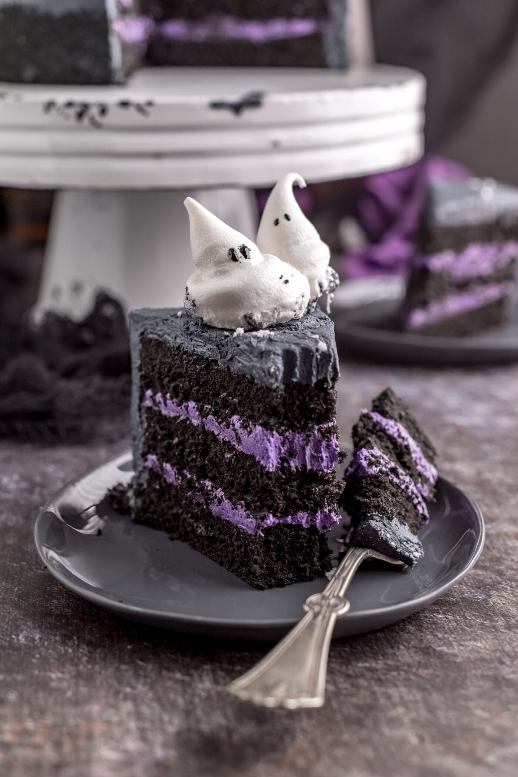 A piece of Halloween Cake on a gray plate with a bite removed.