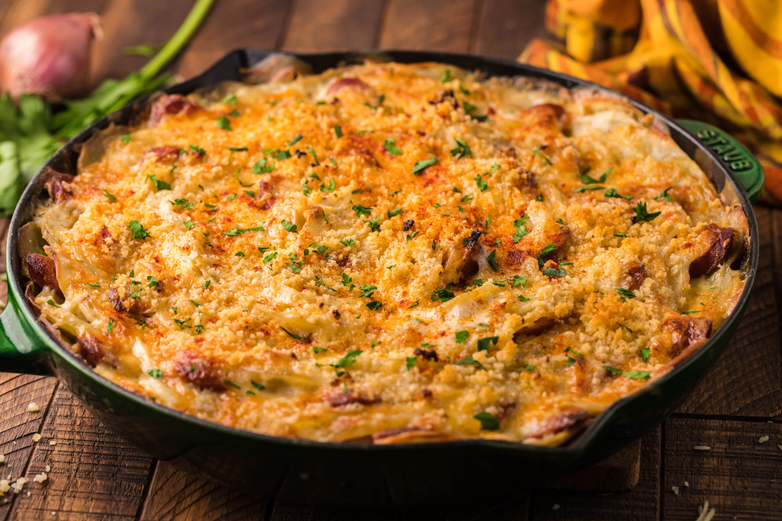 side view Au Gratin Potatoes & Sausage in a cast iron skillet on a wooden table