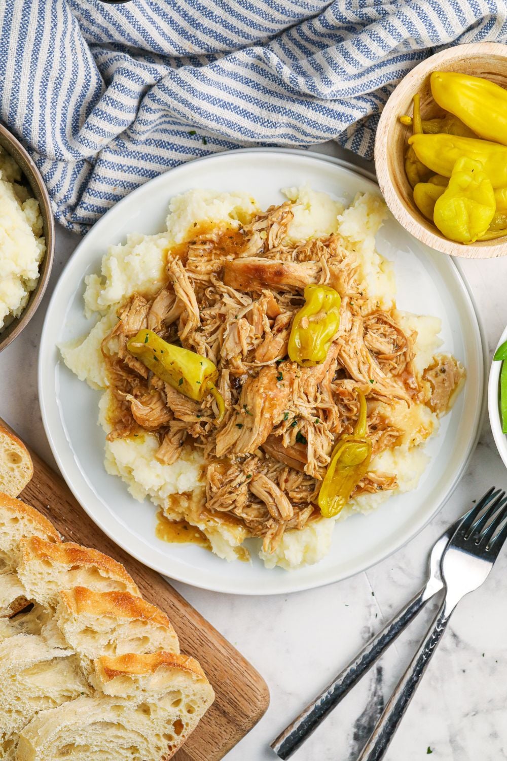 overhead shot of chicken and mashed potatoes on plate with bread and peppers around it