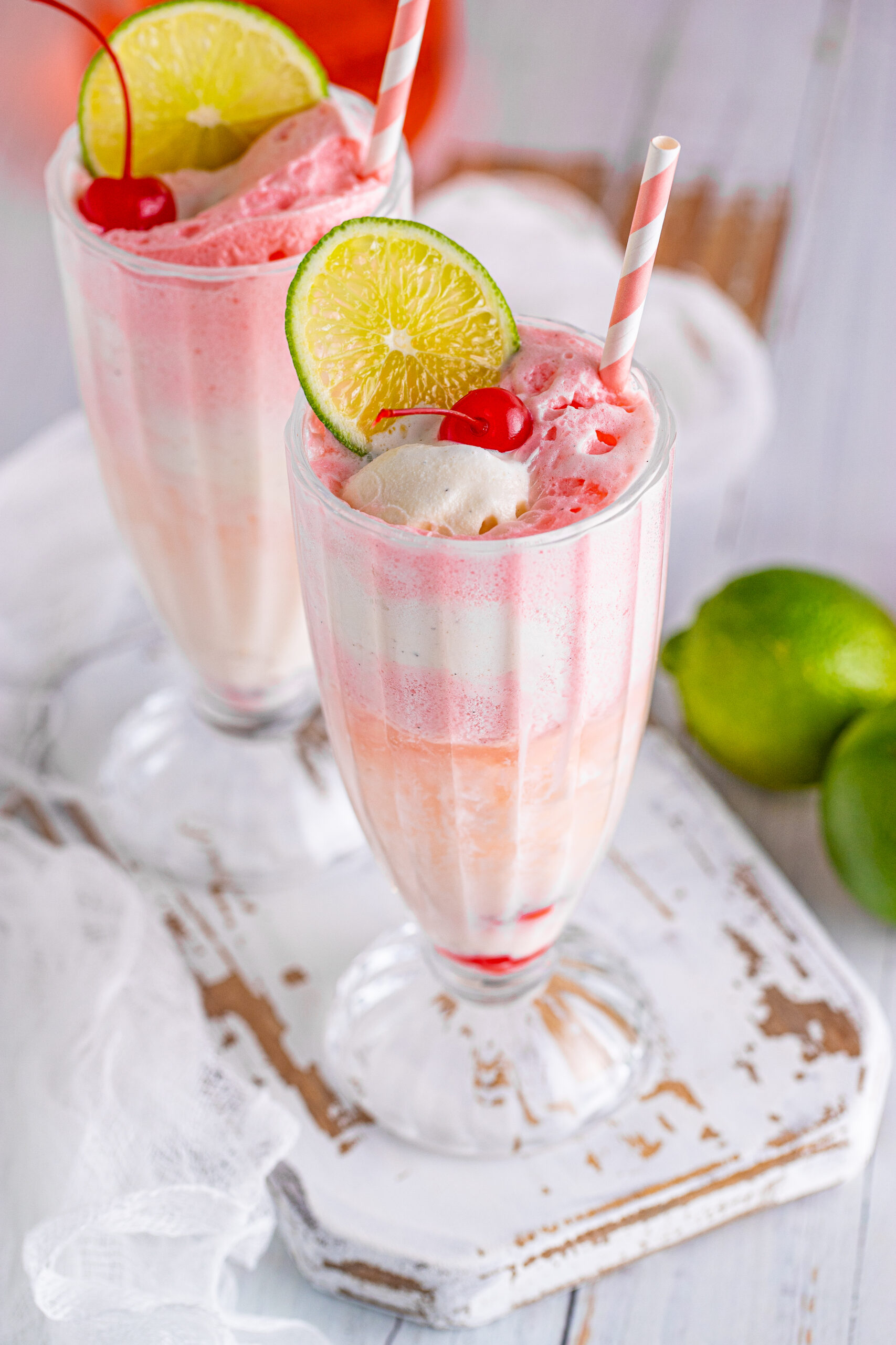 Close up view of Dirty Shirley Float in a clear glass topped with a lime slice and cherry.