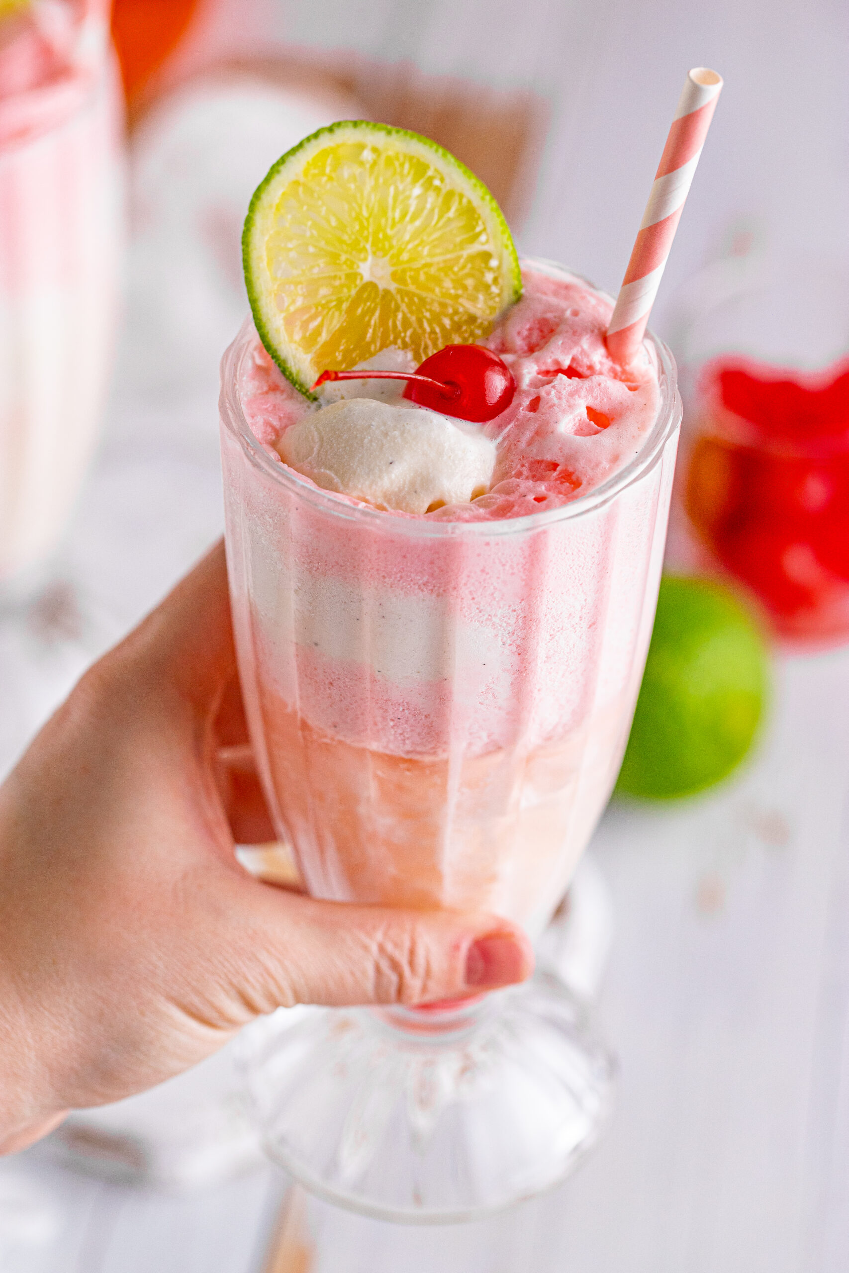 Close up view of Dirty Shirley Float in a clear glass topped with a lime slice and cherry.