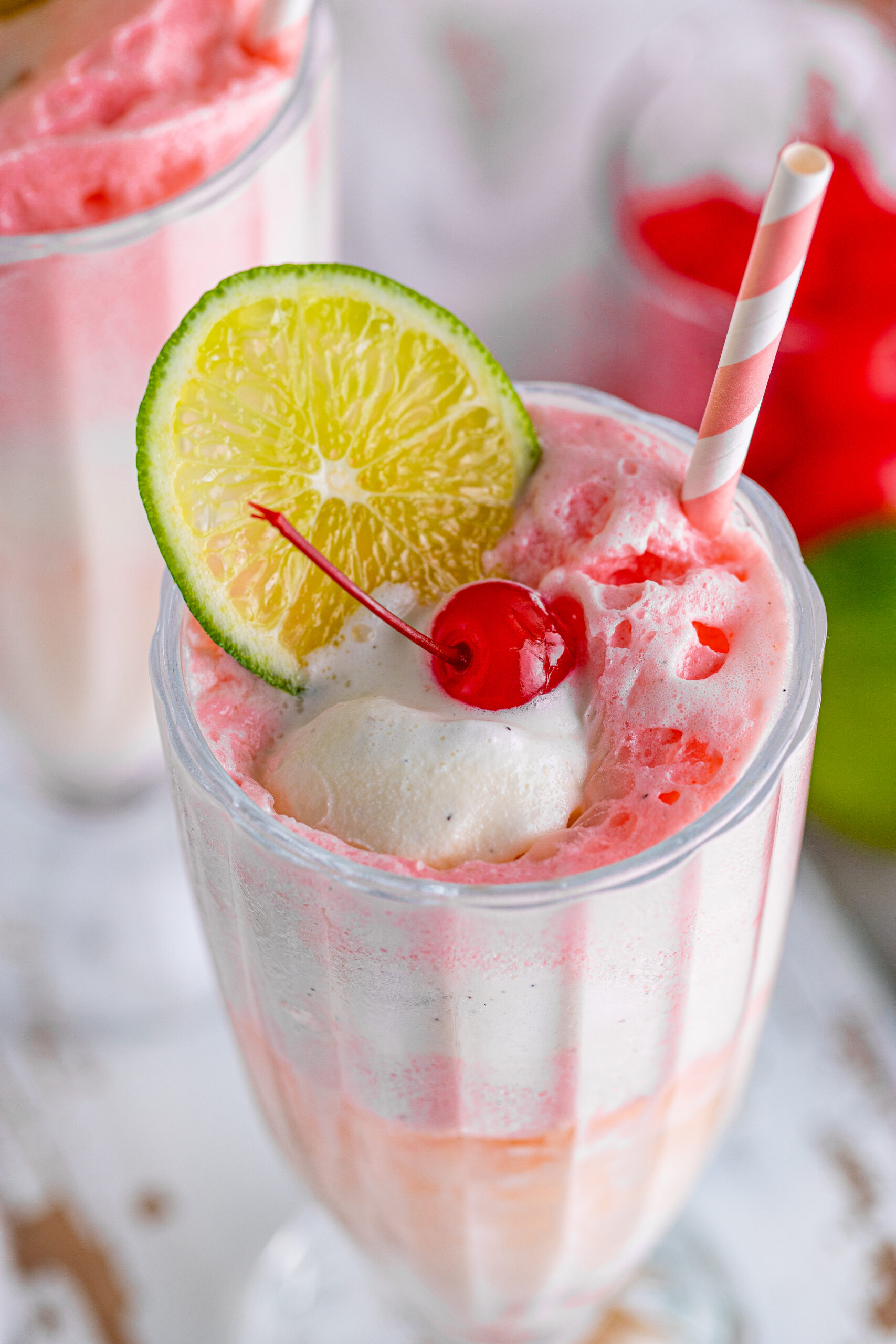 Close up view of Dirty Shirley Float in a clear glass topped with a lime slice and cherry.