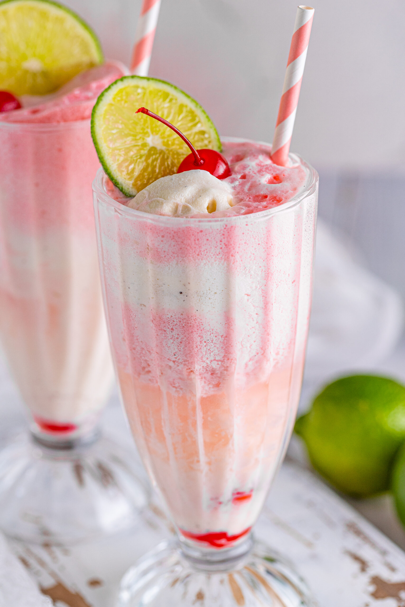 Close up view of Dirty Shirley Float in a clear glass topped with a lime slice and cherry.