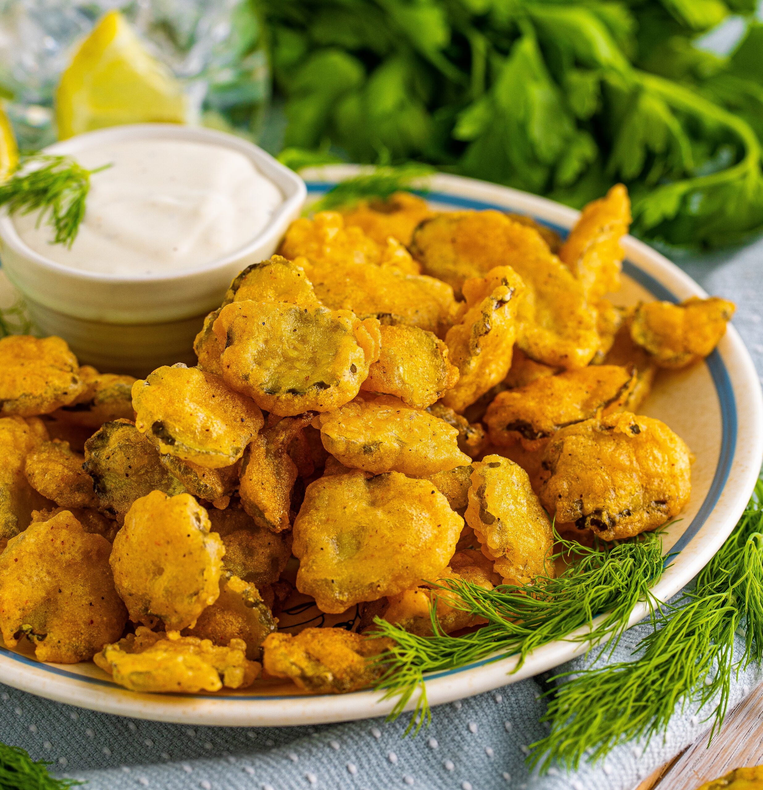 Fried Pickles on a white plate with ranch and fresh dill in the background.