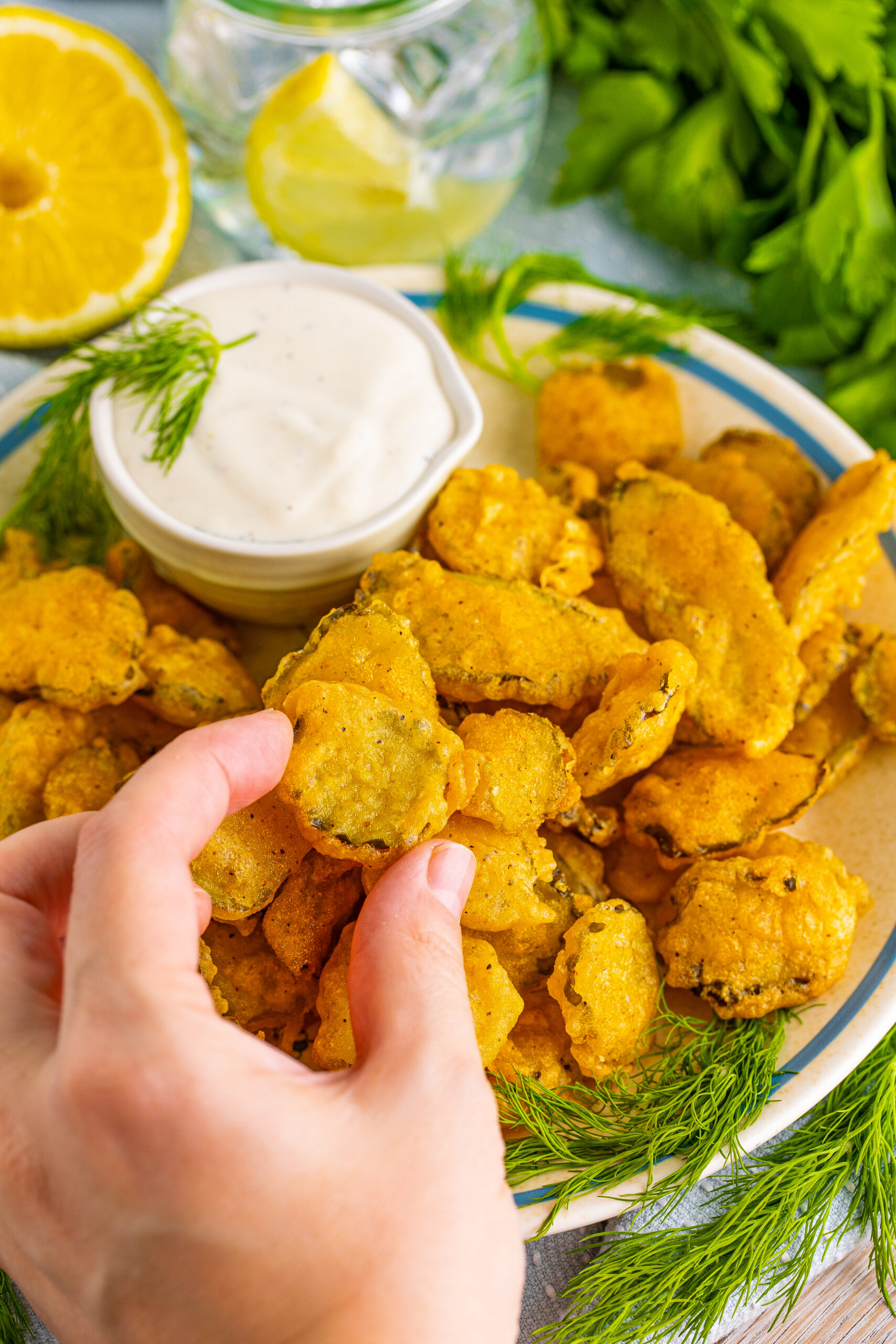 A hand removing a Fried pickle from the plate.