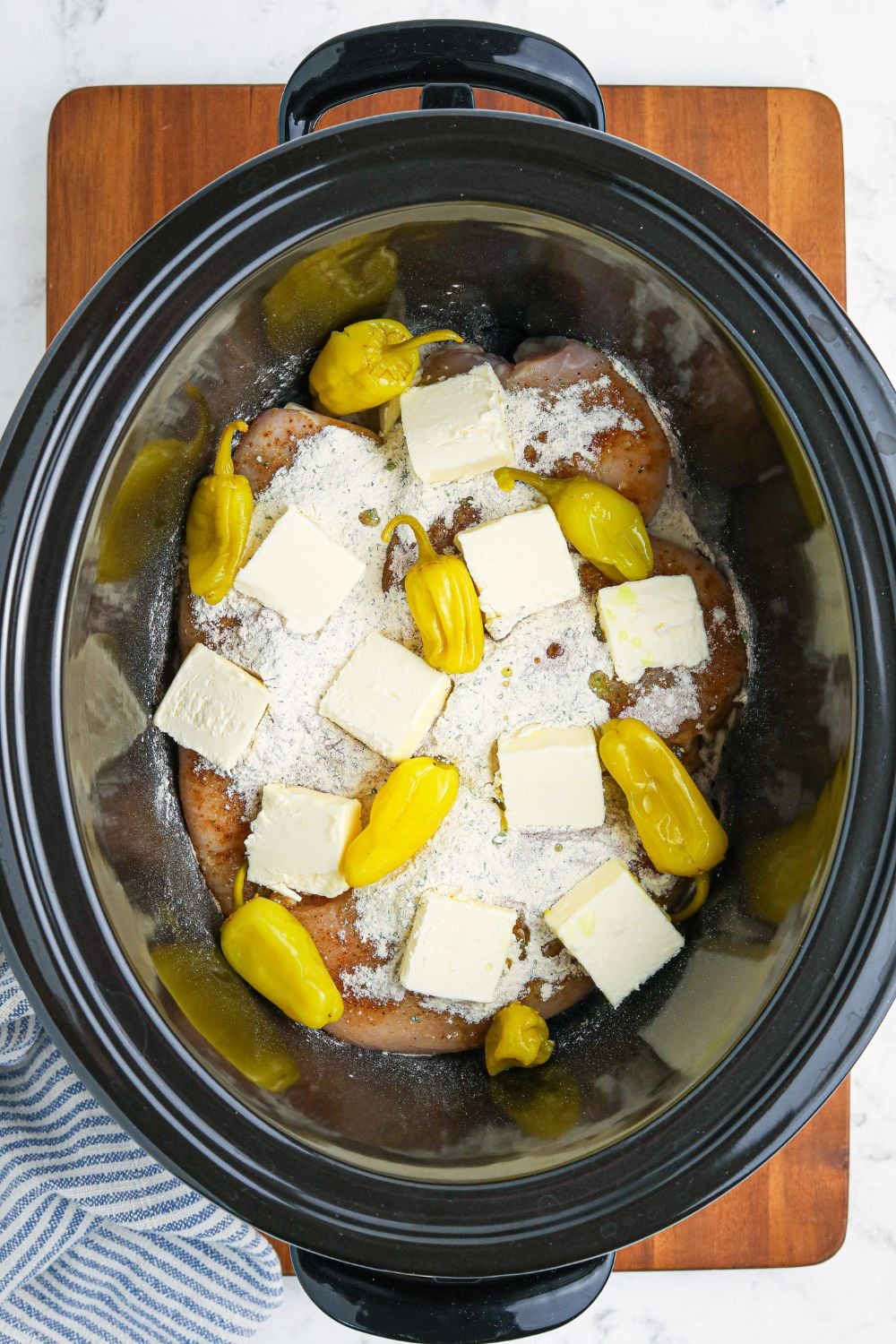 butter and peppers on top of chicken in slow cooker