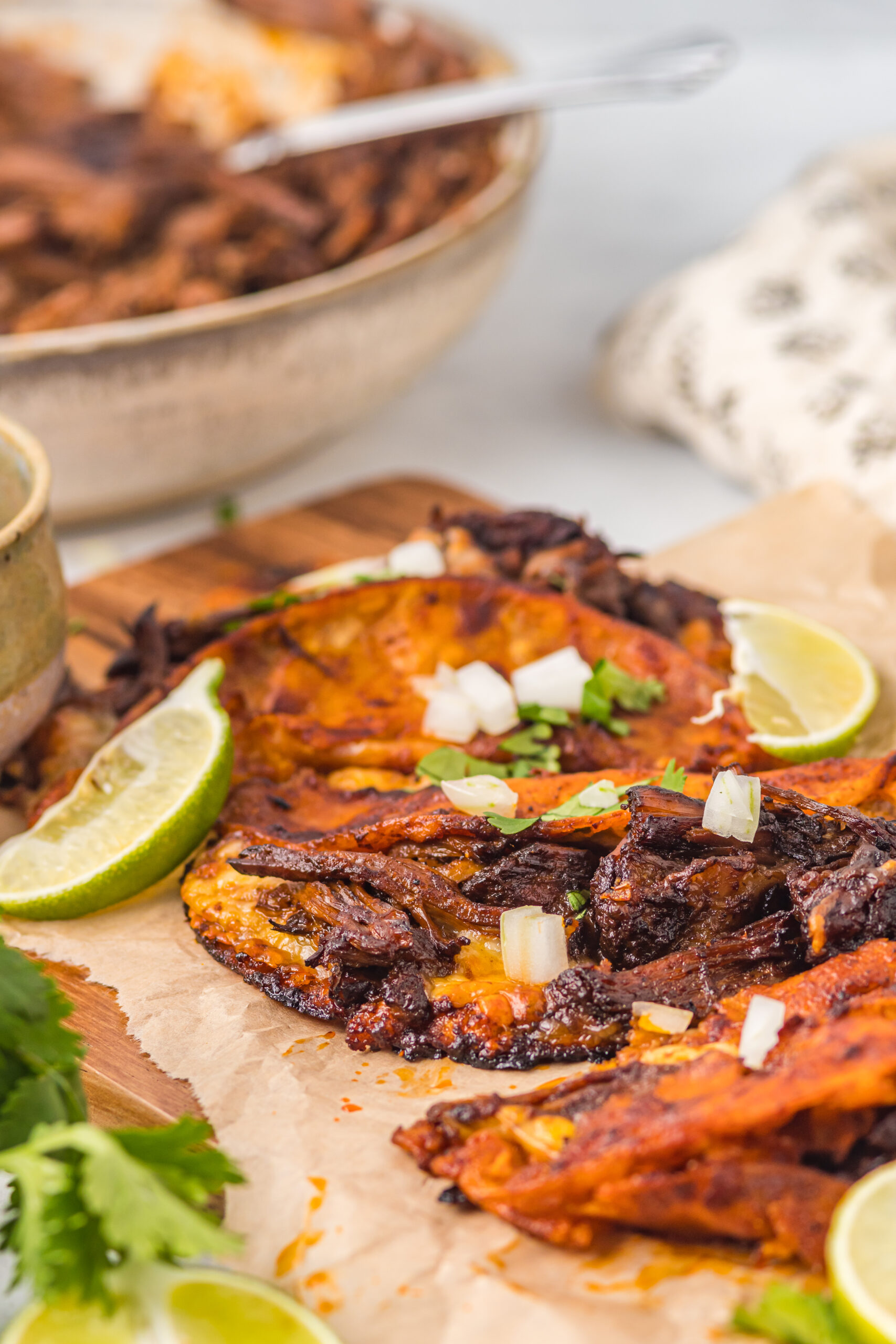 Front view of Birria Tacos on a wooden board garnished with onion and cilantro.