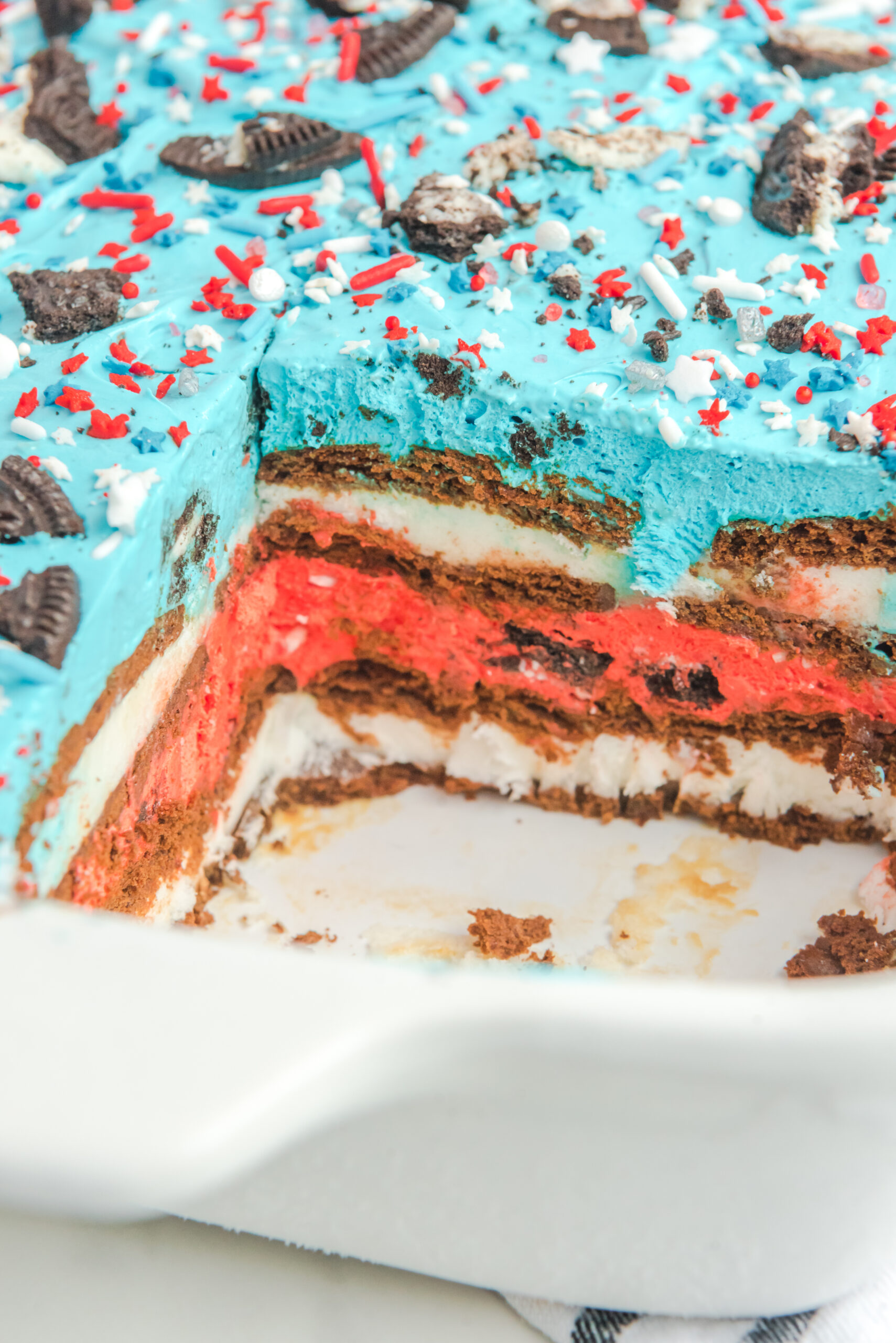Close up view of Patriotic Ice Cream Sandwich Cake in a baking dish with a slice removed.