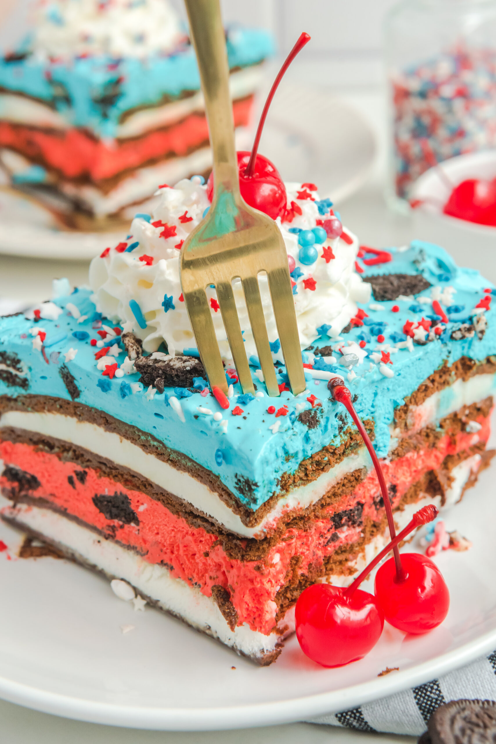 Front view of a slice of Patriotic Ice Cream Sandwich Cake with a silver fork removing a bite.