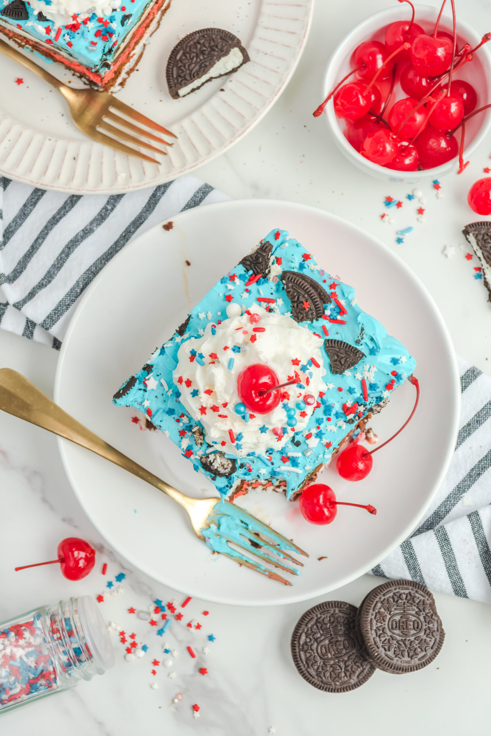 Overhead view of a slice of Patriotic Ice Cream Sandwich Cake with a bite removed by a silver fork.