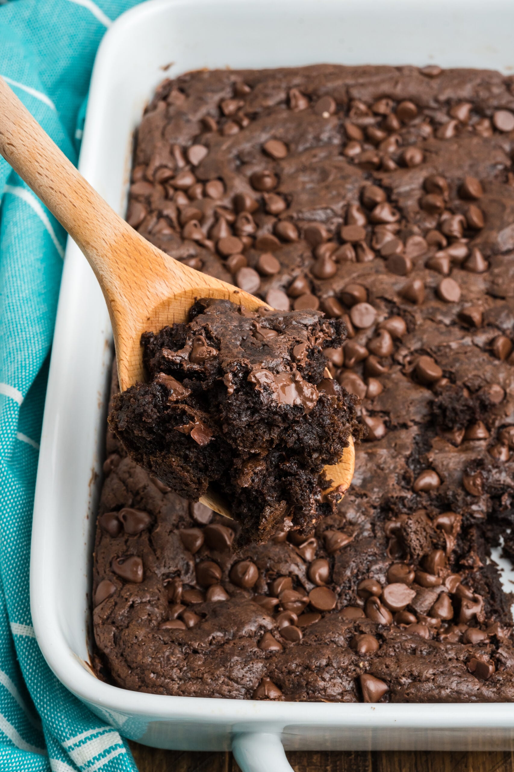 Close up view of a wooden spoon removing a serving of Chocolate Dump Cake.