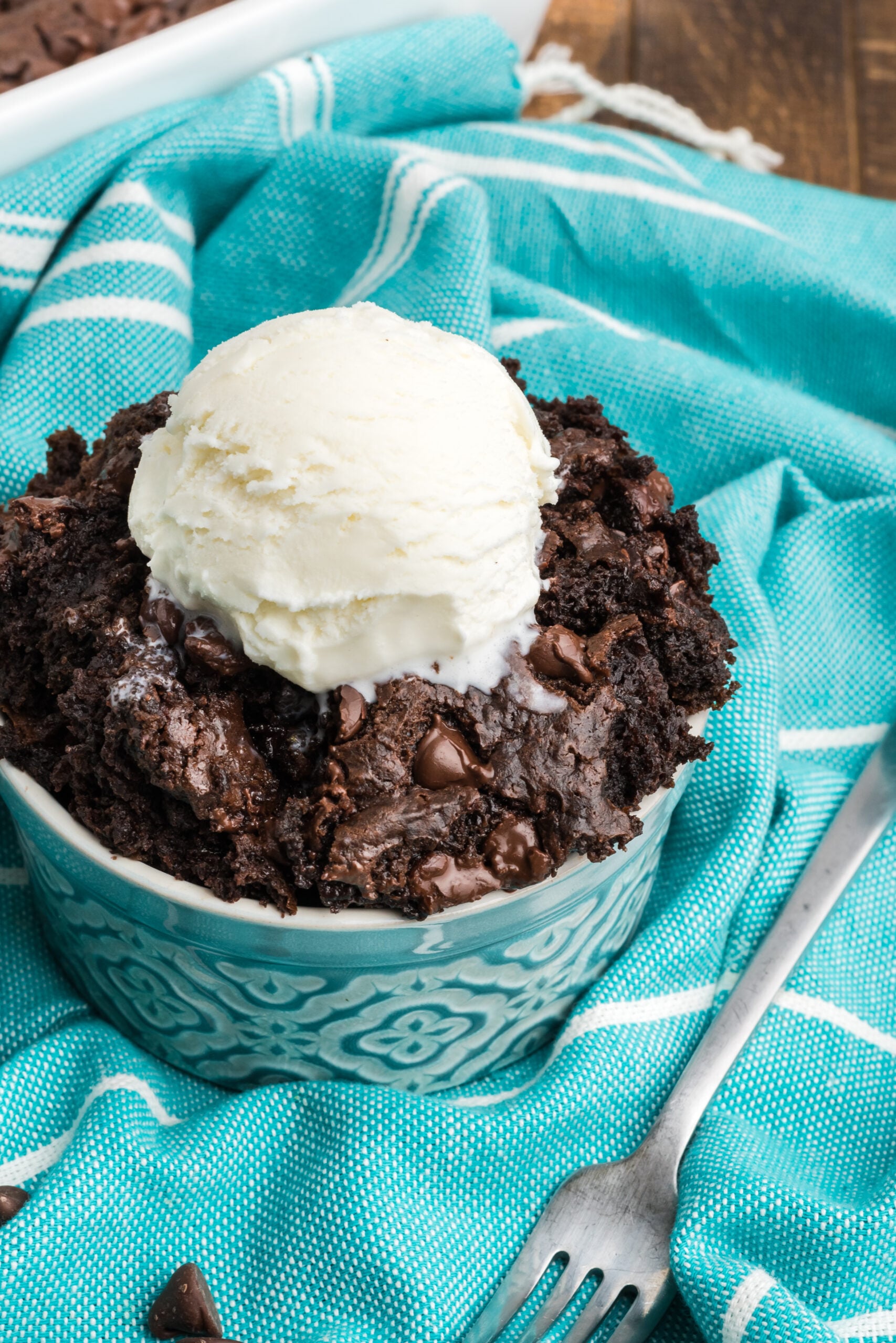 Close up view of a serving of Chocolate Dump Cake in a bowl topped with a scoop of ice cream.