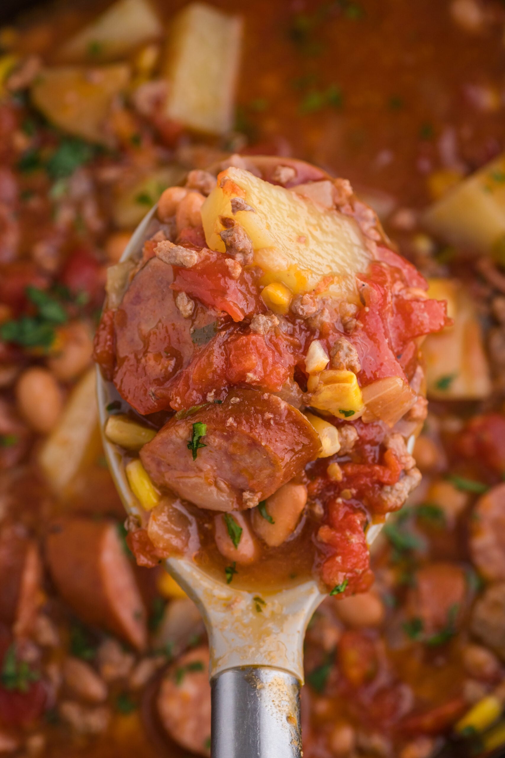 Close up view of a spoon removing a serving of Slow Cooker Texas Cowboy Stew.