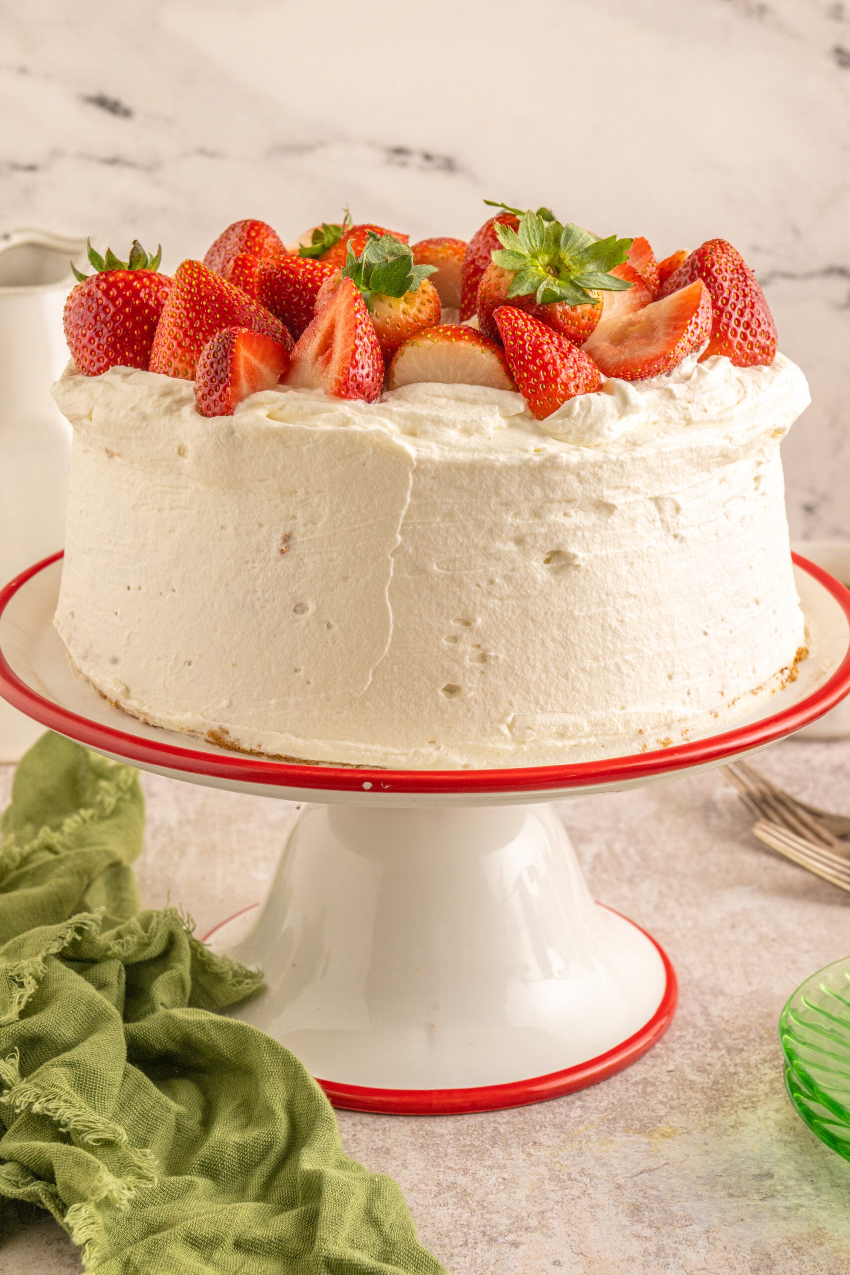 Strawberry Angel Food Cake topped with fresh strawberries and on a cake stand