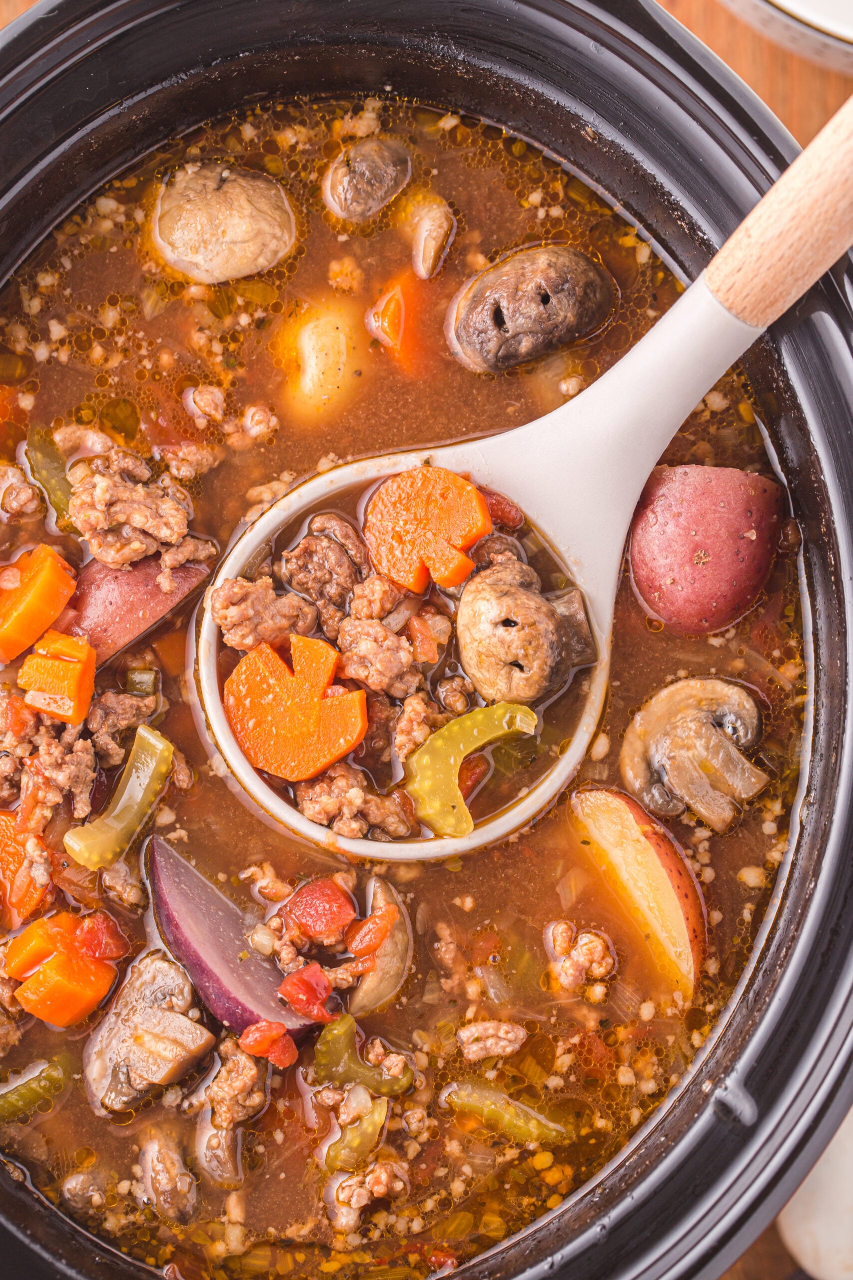 Overhead view of a serving spoon removing a serving of Witches Brew Stew.